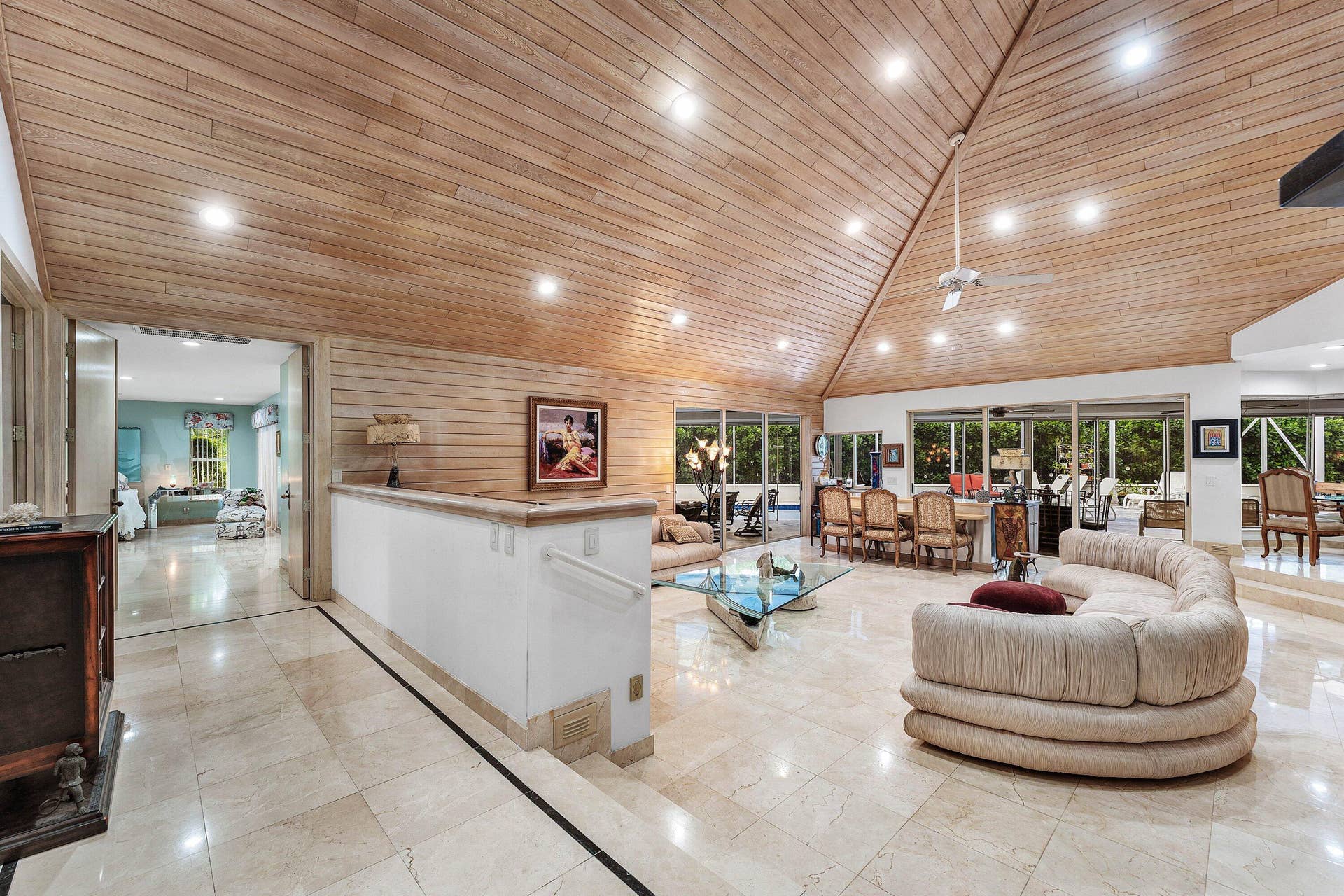 56 NORTHWOODS Lane, Boynton Beach, FL 33436 Vaulted wood-paneled ceiling with recessed lighting, stone tile flooring, half-wall with handrail, and expansive glass sliding doors