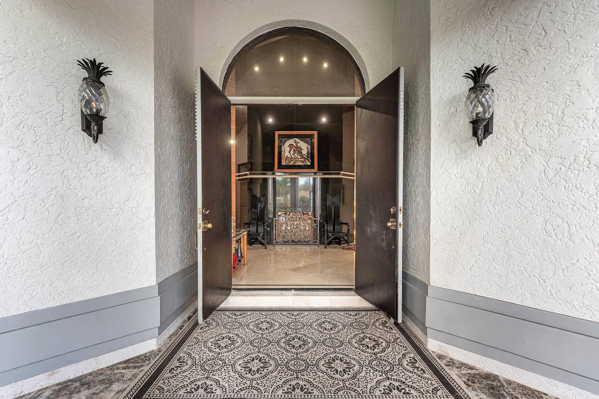 56 NORTHWOODS Lane, Boynton Beach, FL 33436 Arched entry with double doors, pineapple-motif sconces, and patterned inlay flooring