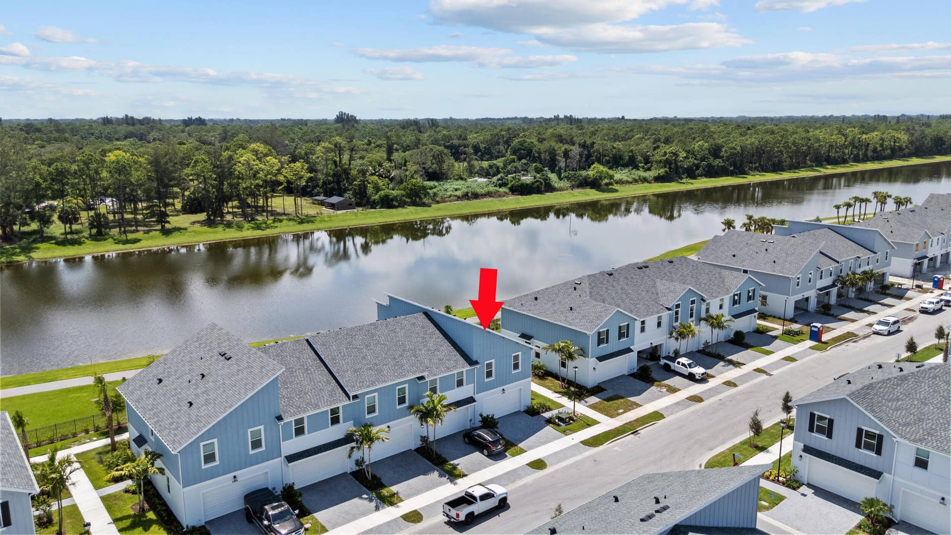 Waterfront townhome community with a modern architectural design, individual garages, and paved driveways