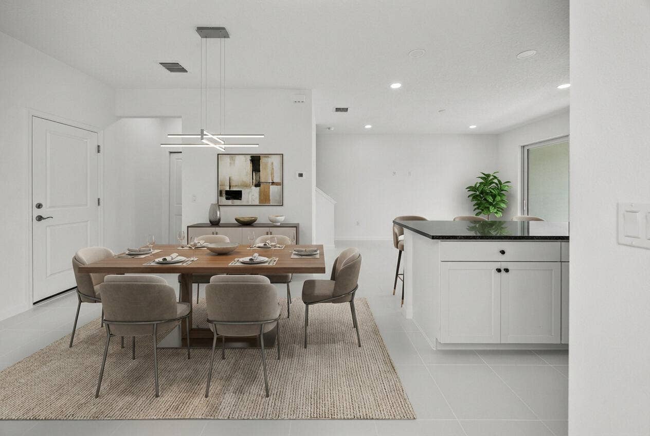 Modern linear chandelier, built-in recessed lighting, white cabinetry, dark stone countertop, and light tile flooring