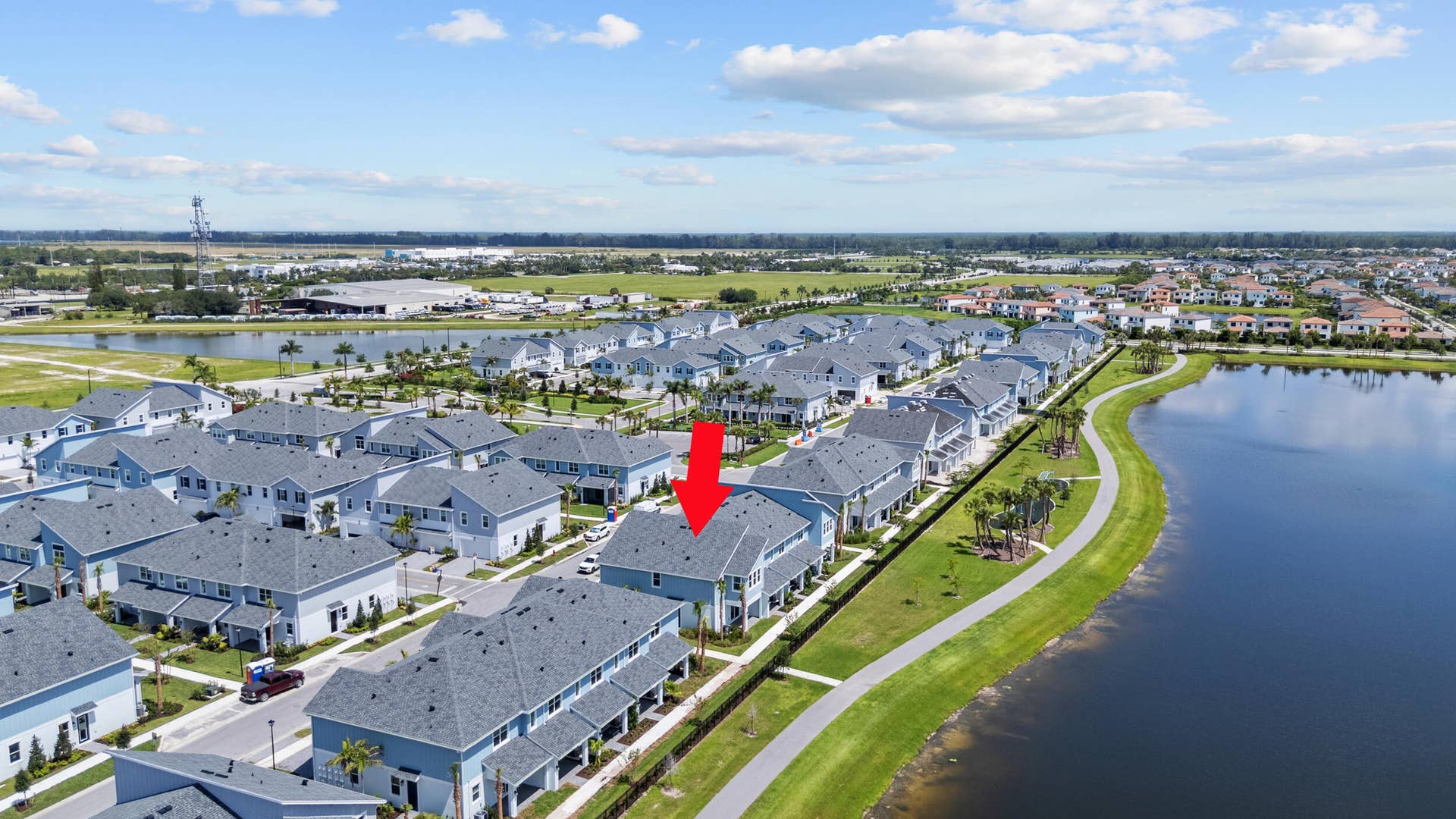 Waterfront property featuring a private driveway, attached garages, and a paved walkway