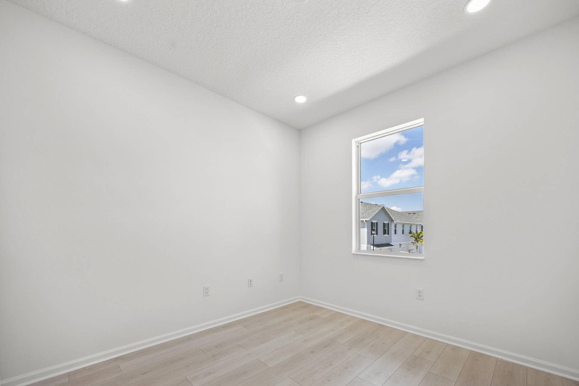 Recessed ceiling lighting, light wood-finish flooring, and a window with white trim