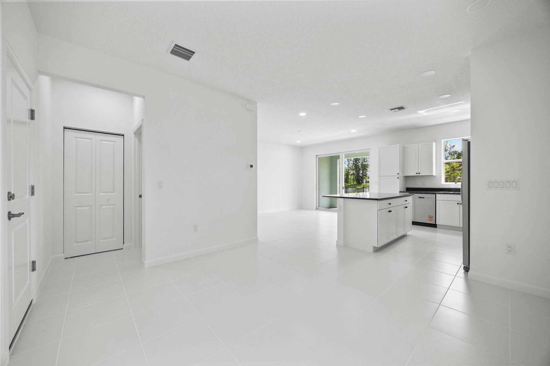 Open-concept living area with large format tile flooring and white walls