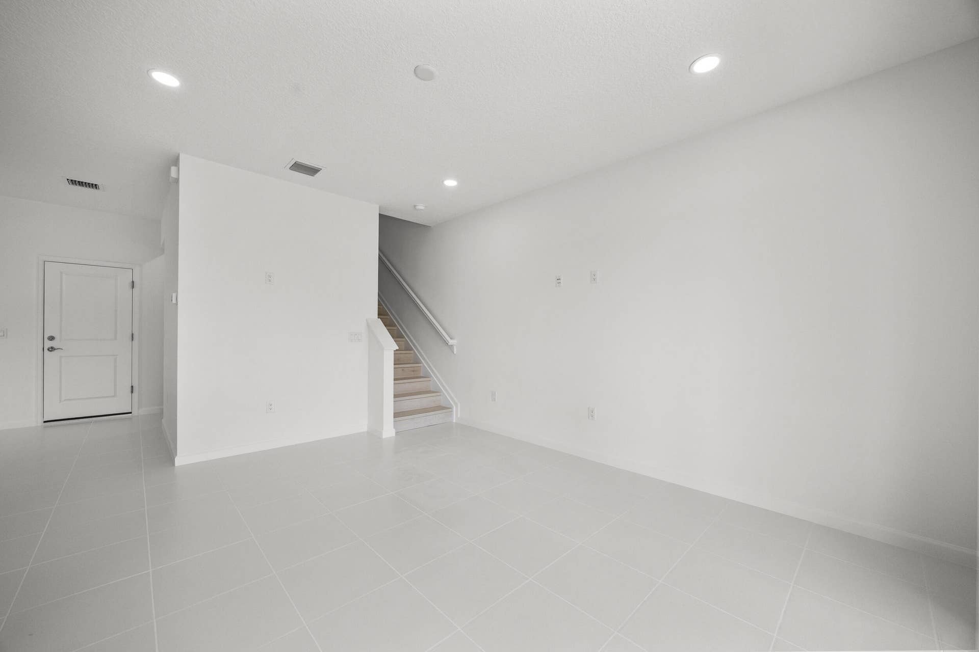 Recessed lighting, light-toned tile flooring, and a staircase with a white railing