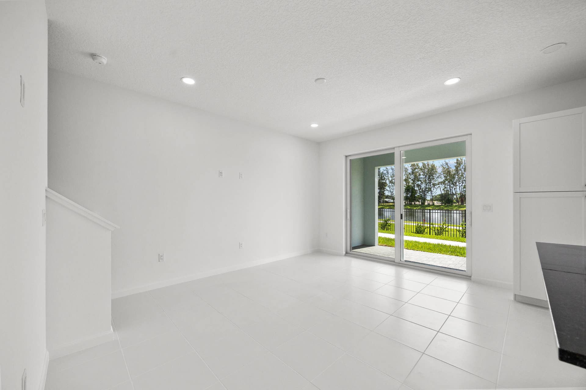 White tile flooring, recessed lighting, sliding glass door, white cabinetry, dark countertop