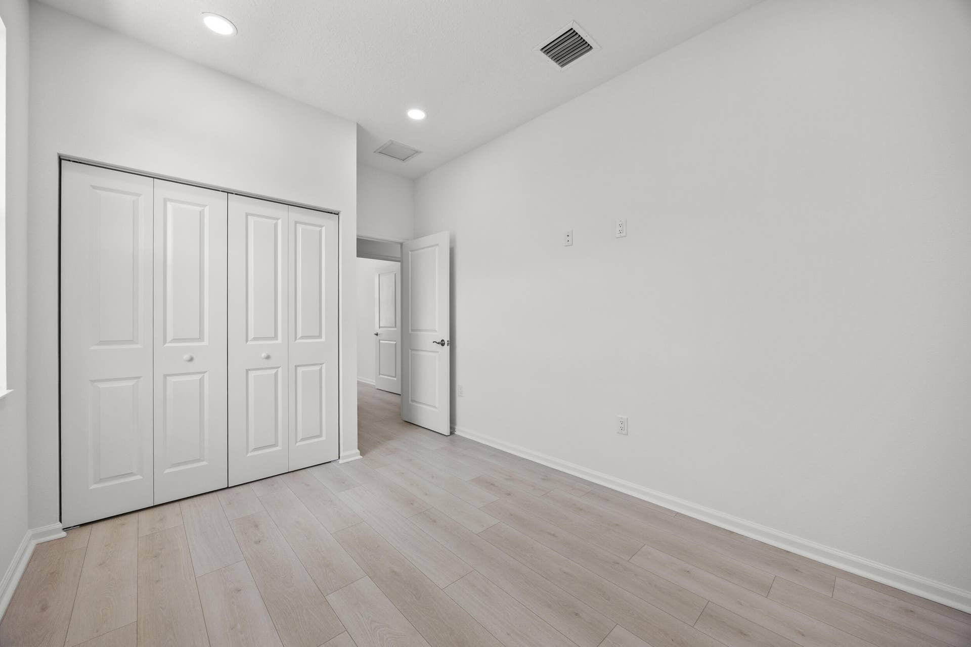 Recessed lighting, light wood-finish flooring, white walls, and bi-fold closet doors