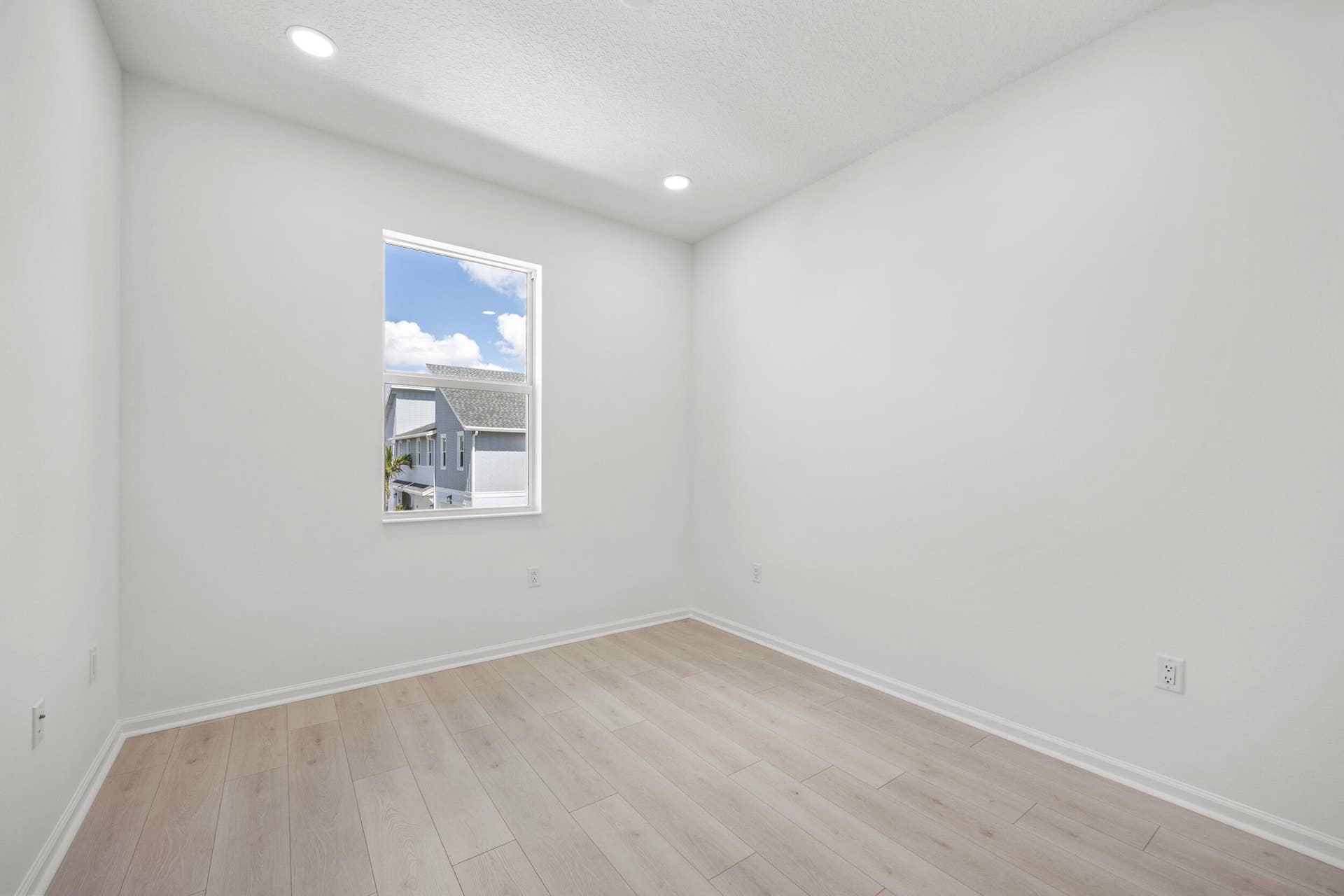 Recessed ceiling lighting, wood-finish flooring, white baseboards, and a single window with white trim