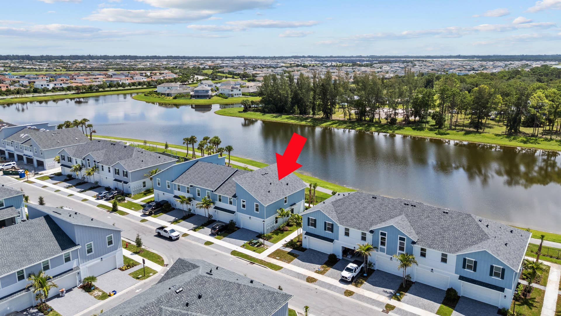 Waterfront property featuring a private driveway, attached garages, and a paved walkway