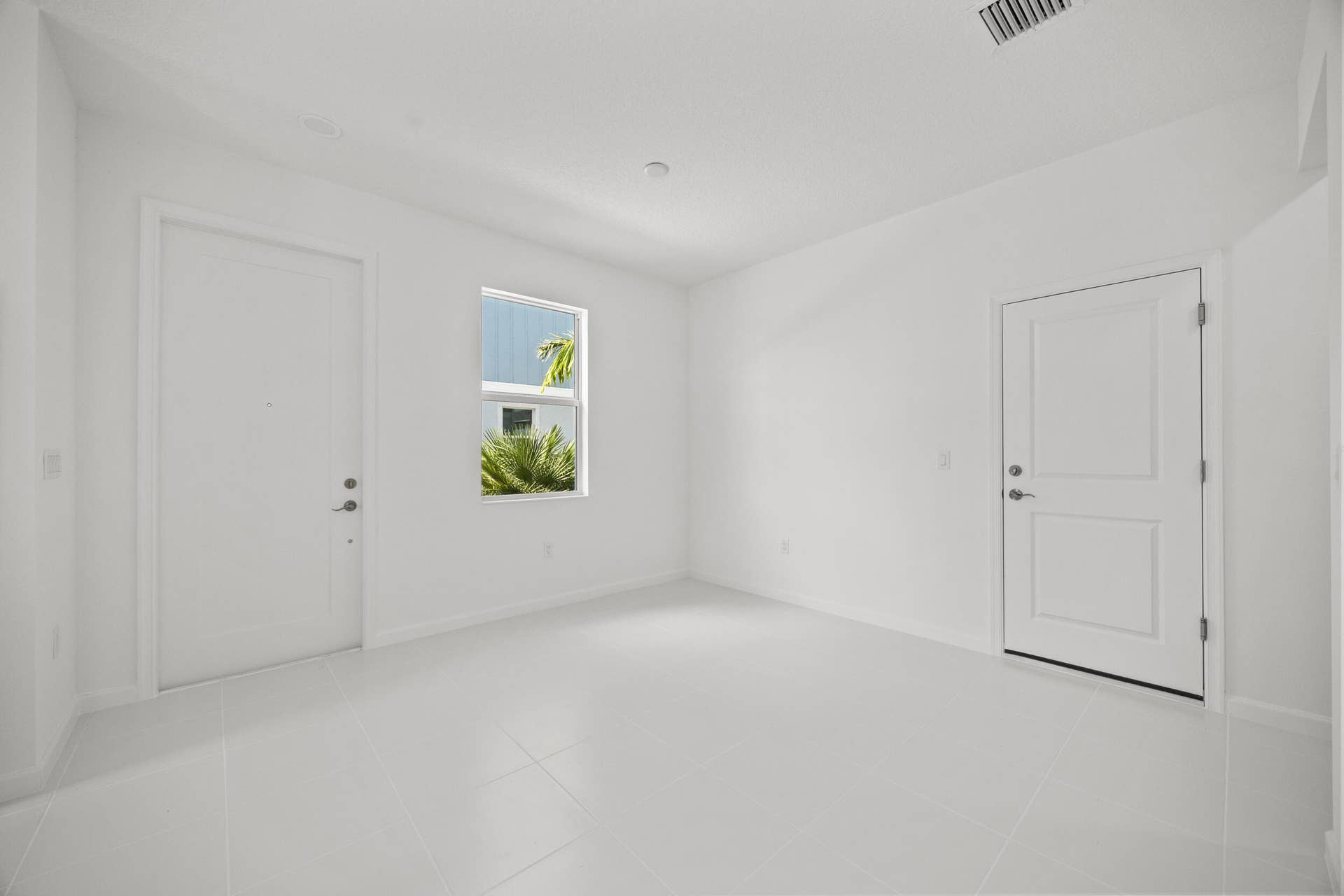 White tile flooring, white walls, recessed ceiling lighting, and a single window