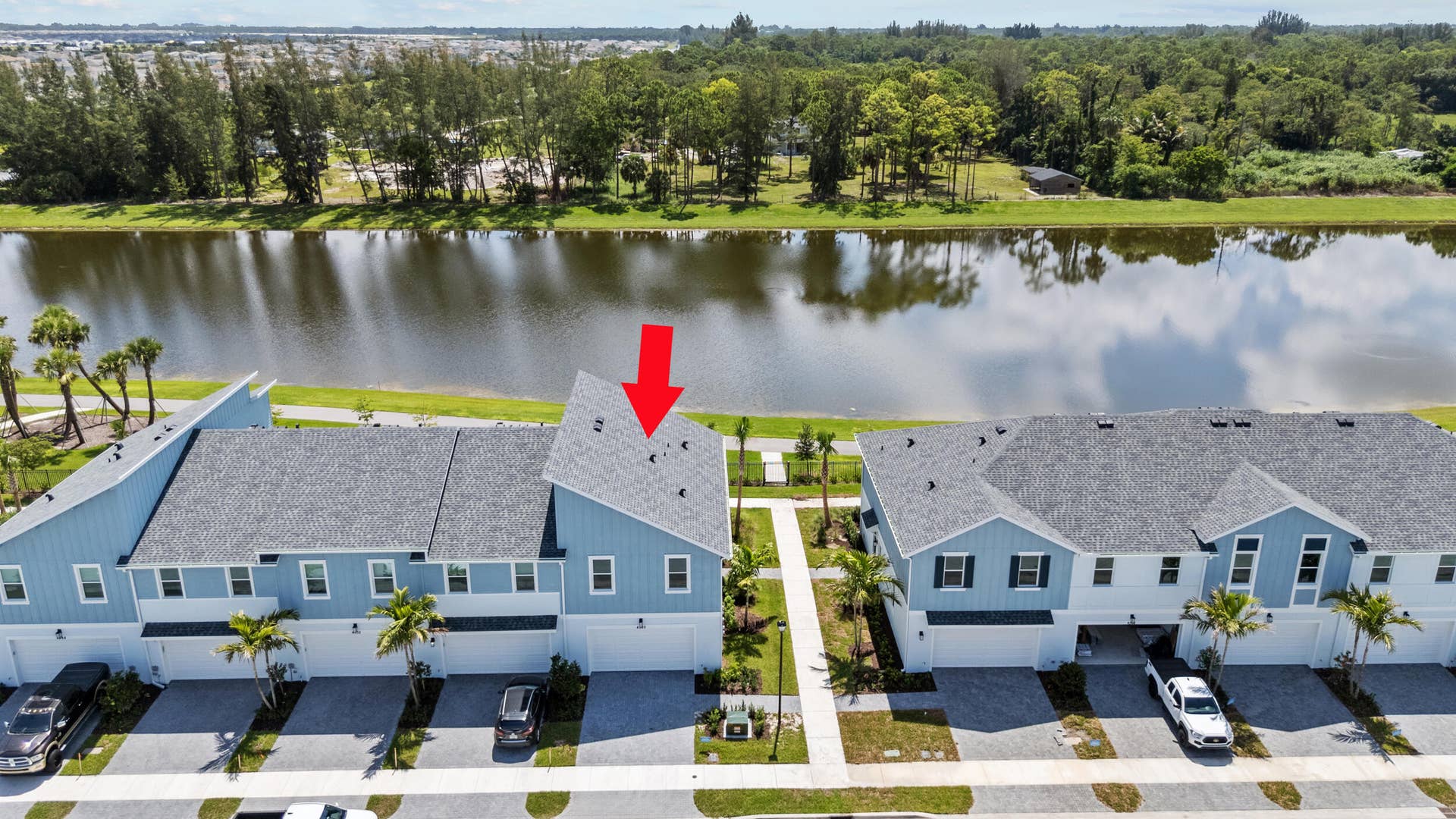 Two-story property with light blue and white siding, individual garages, and paver driveways