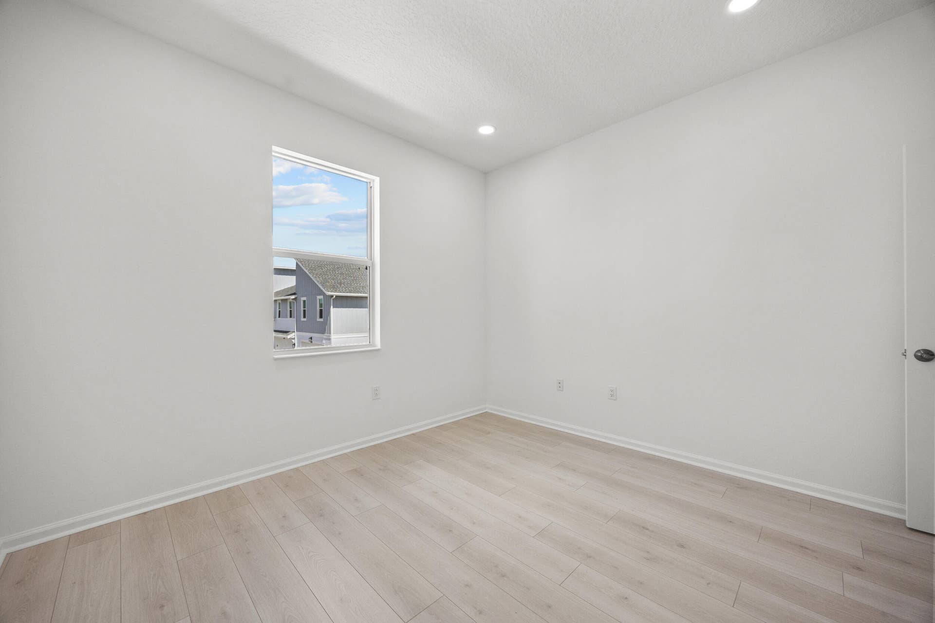 Wood-finish flooring, recessed lighting, white walls, and a window with natural light