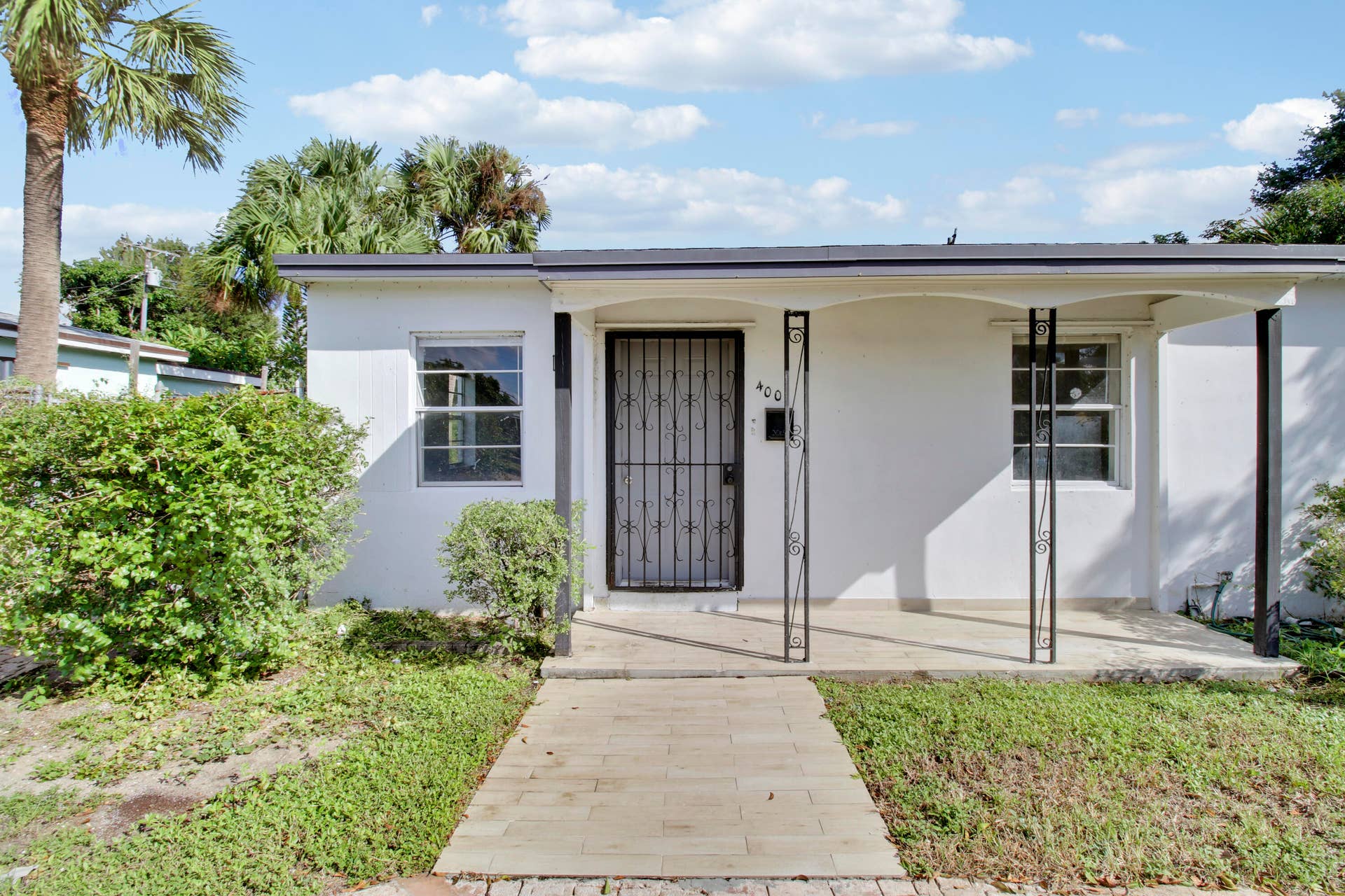 White stucco exterior with a covered porch featuring wrought iron columns