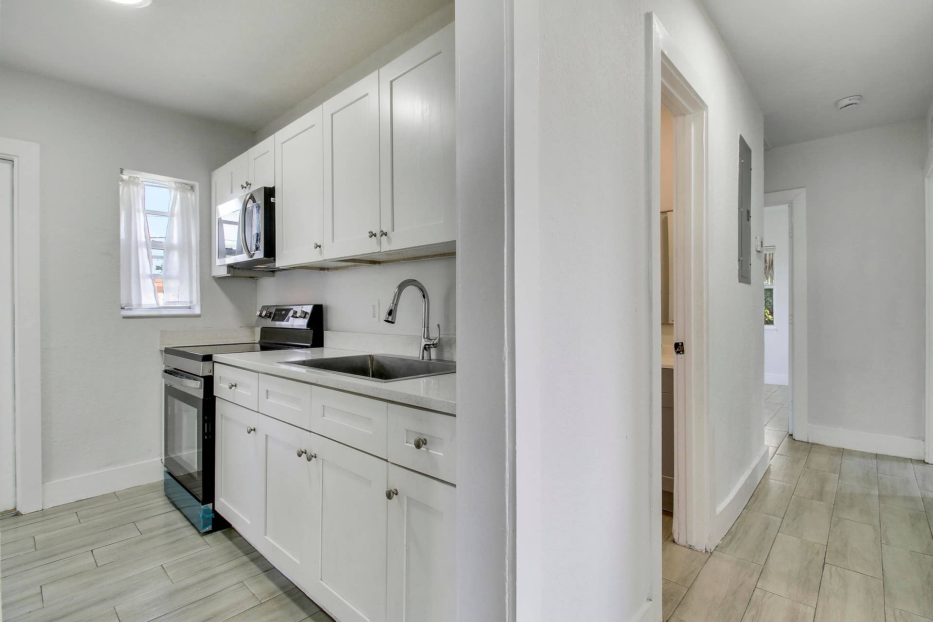 Kitchen featuring white cabinetry, stainless steel sink, and light-toned countertops
