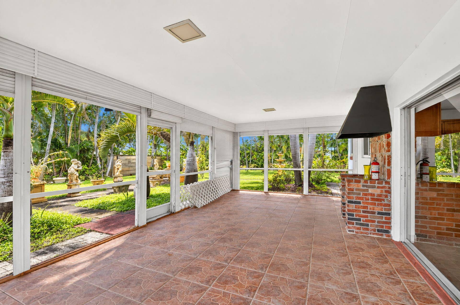 Screened enclosure with tile flooring, brick-faced built-in counter, and a permanent range hood