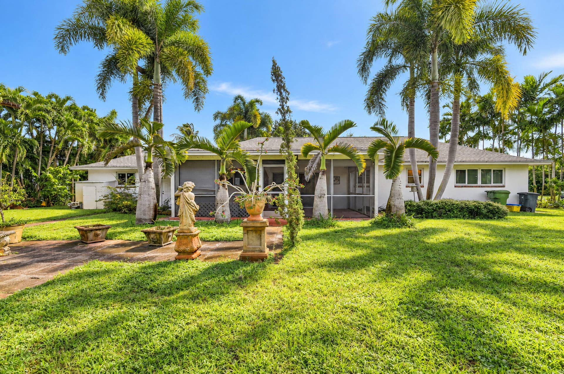 Expansive green lawn with mature palm trees and a screened-in porch