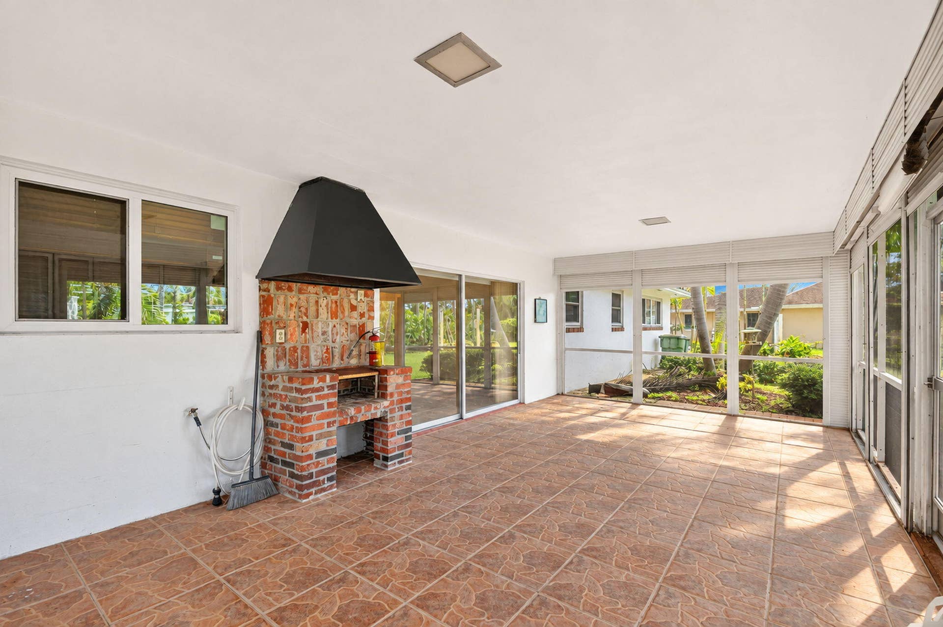 Screened patio with tile flooring, built-in brick barbecue, and sliding glass doors