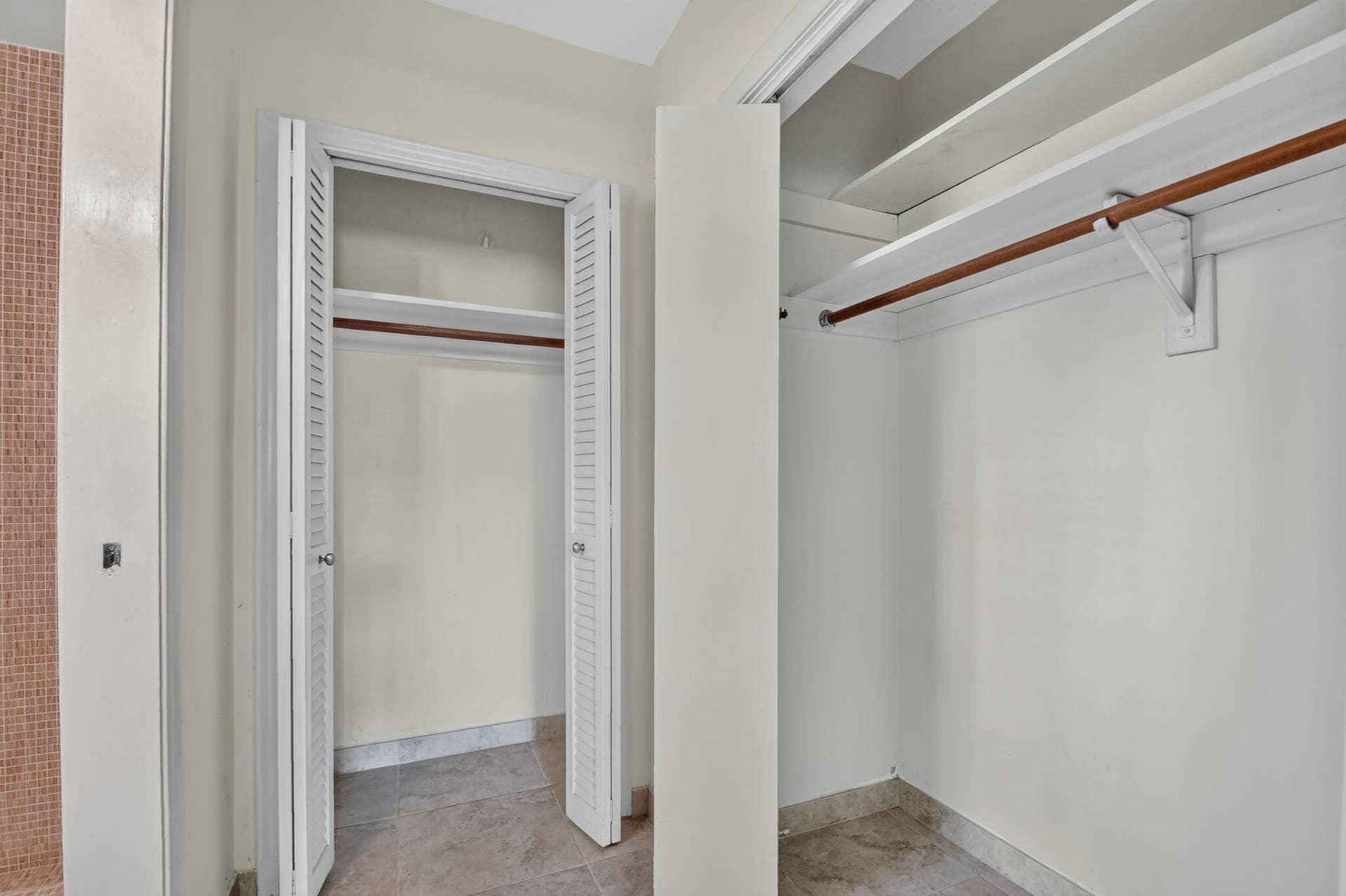 Dual closets with louvered bifold doors, featuring integrated shelving and clothing rods