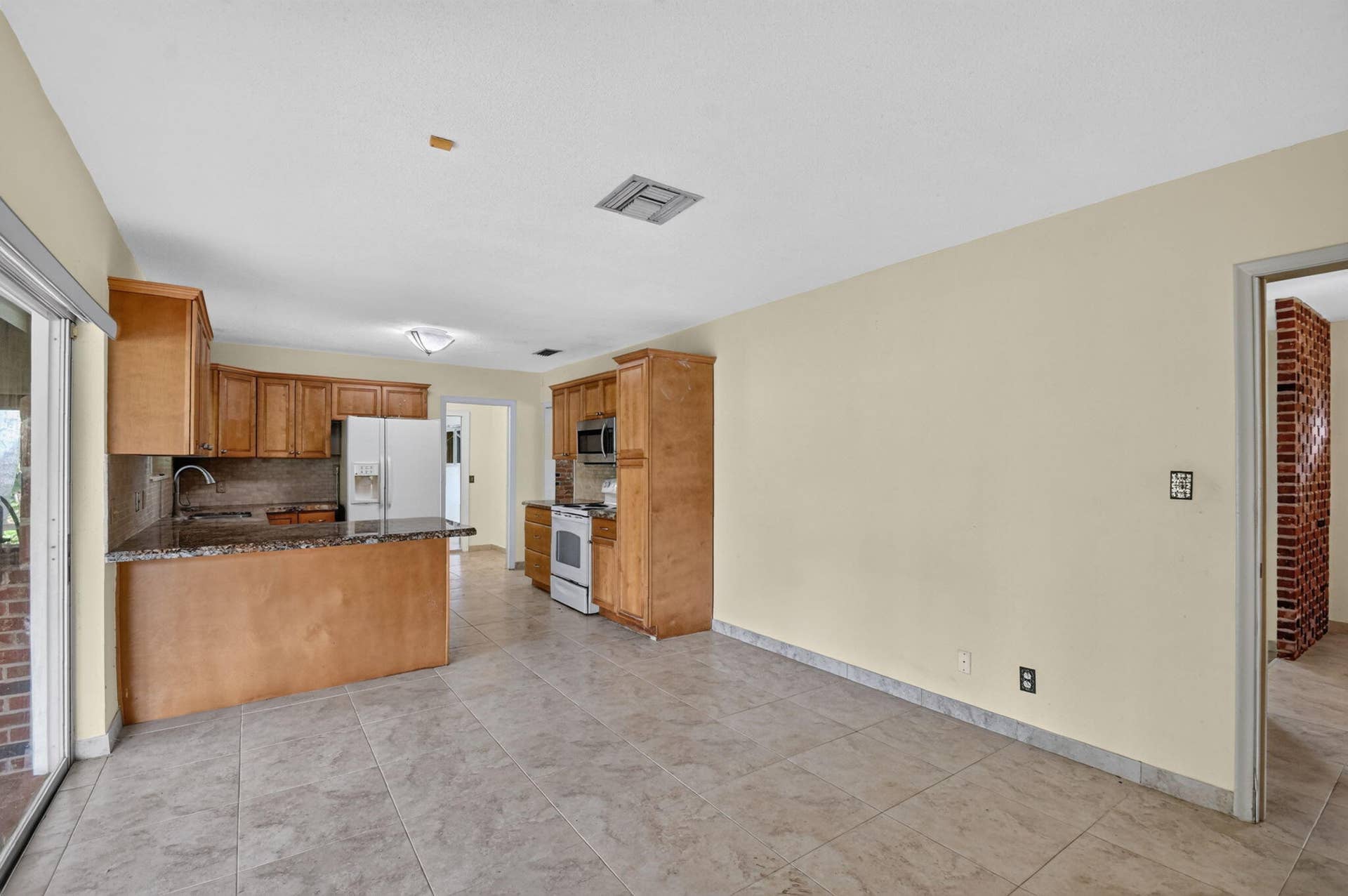 Kitchen featuring wooden cabinetry, white appliances, granite-style countertops, and tile flooring