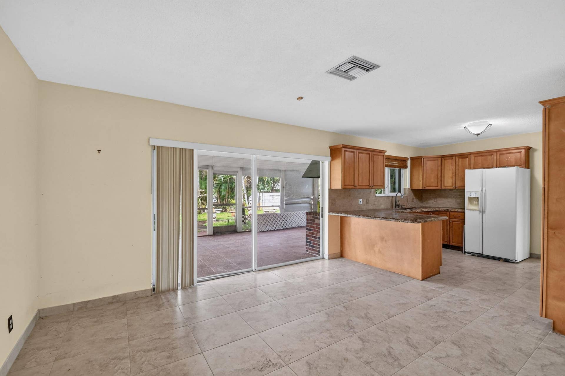 Kitchen with wood cabinetry, stone countertops, and tile flooring