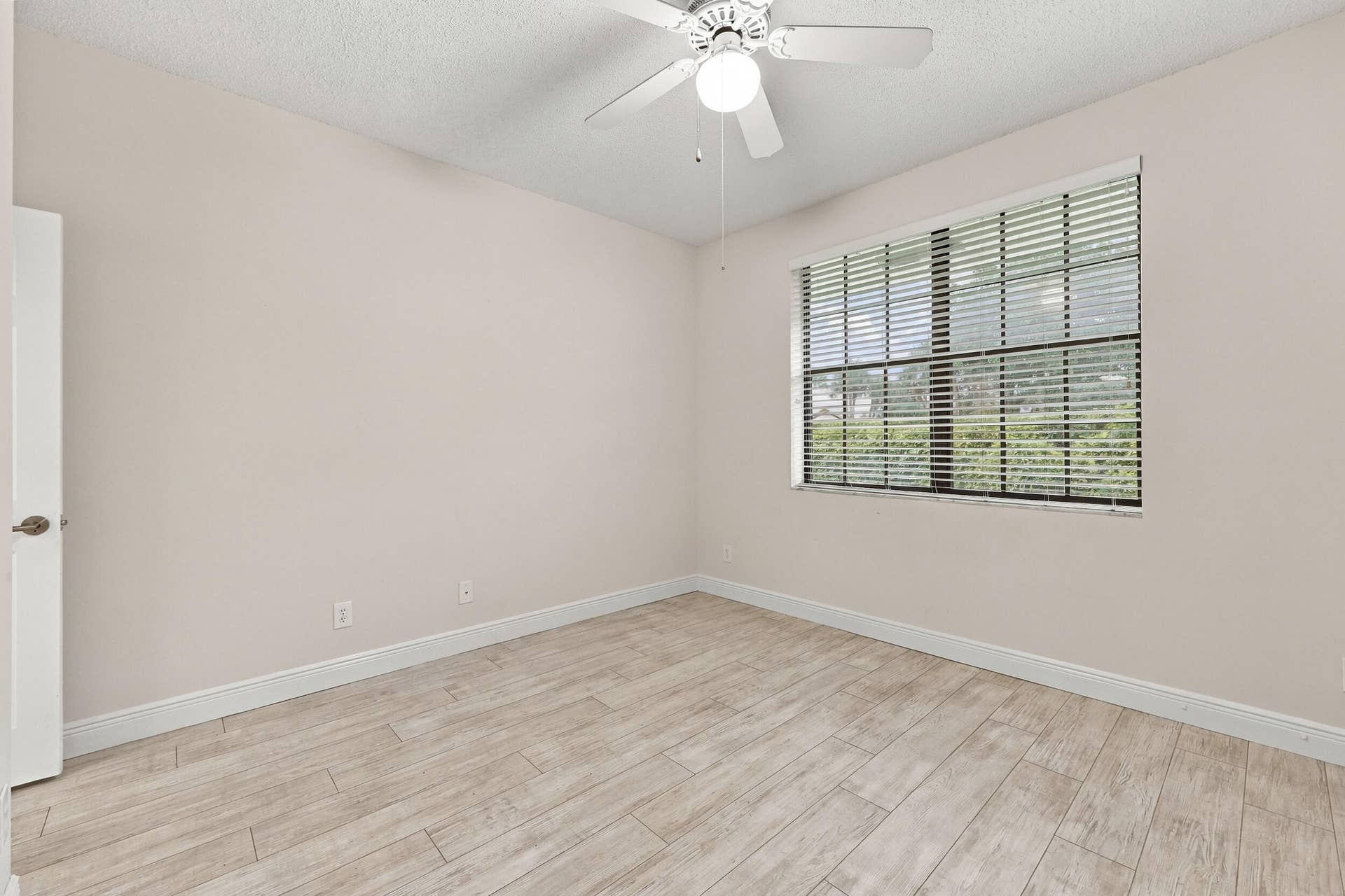 8292 WATERLINE Drive, #106, Boynton Beach, FL 33472 Neutral wall tones, wood-finish flooring, ceiling fan with integrated lighting, window with horizontal blinds, and white trim throughout