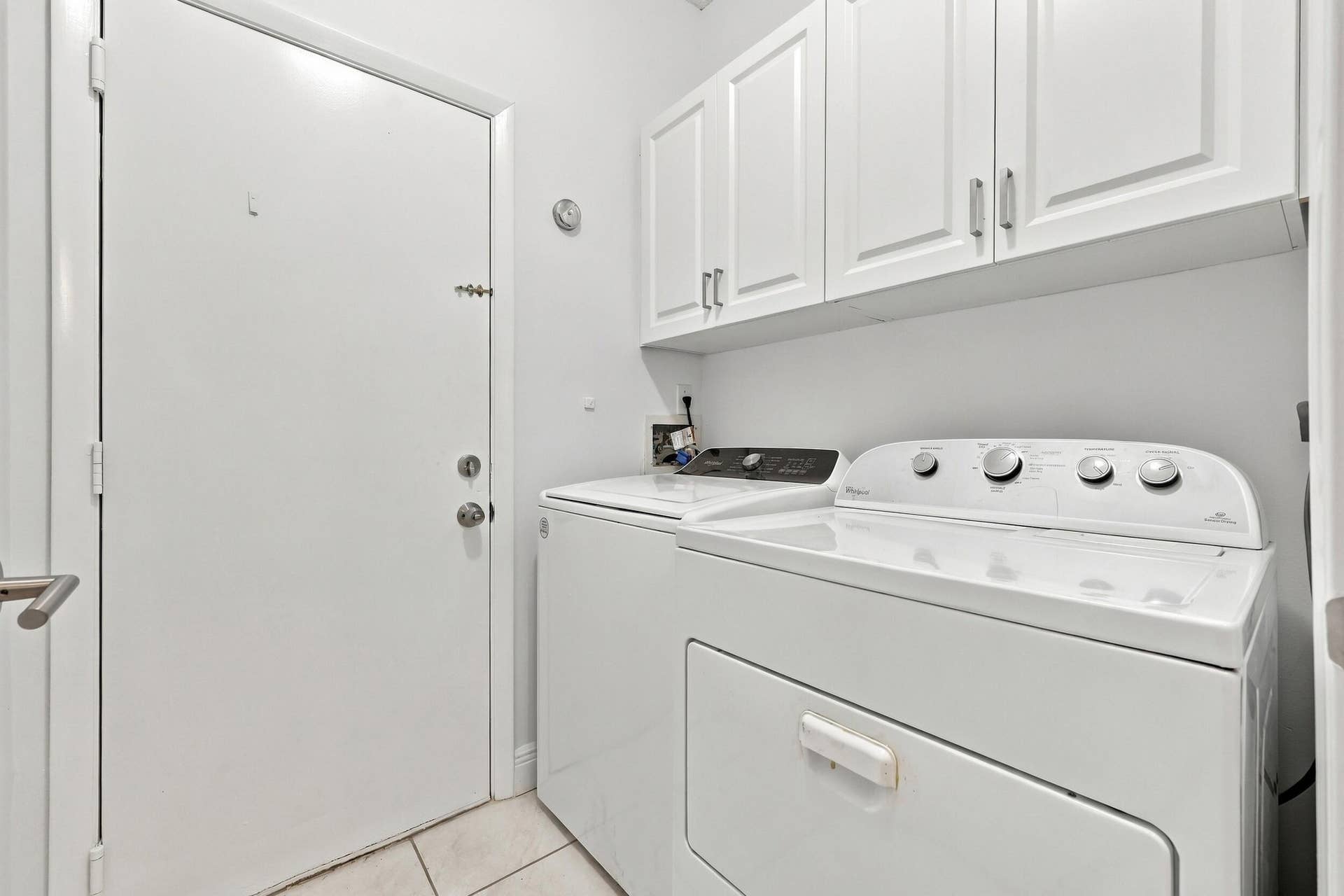 8292 WATERLINE Drive, #106, Boynton Beach, FL 33472 Laundry area with white cabinetry, tile flooring, and a white door