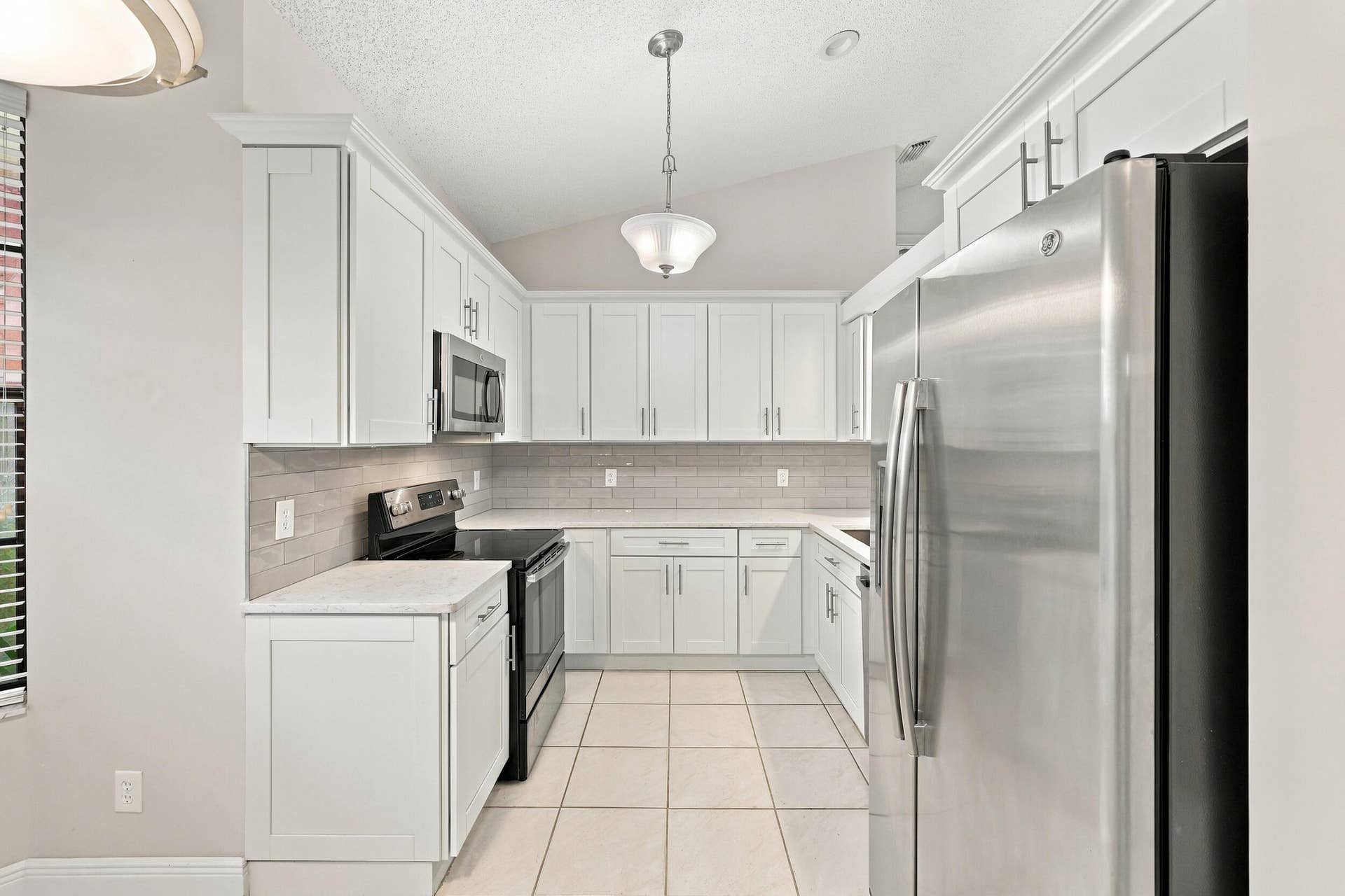 8292 WATERLINE Drive, #106, Boynton Beach, FL 33472 Kitchen featuring white shaker cabinetry, stainless steel appliances, light-toned countertops, tile flooring, and a tiled backsplash