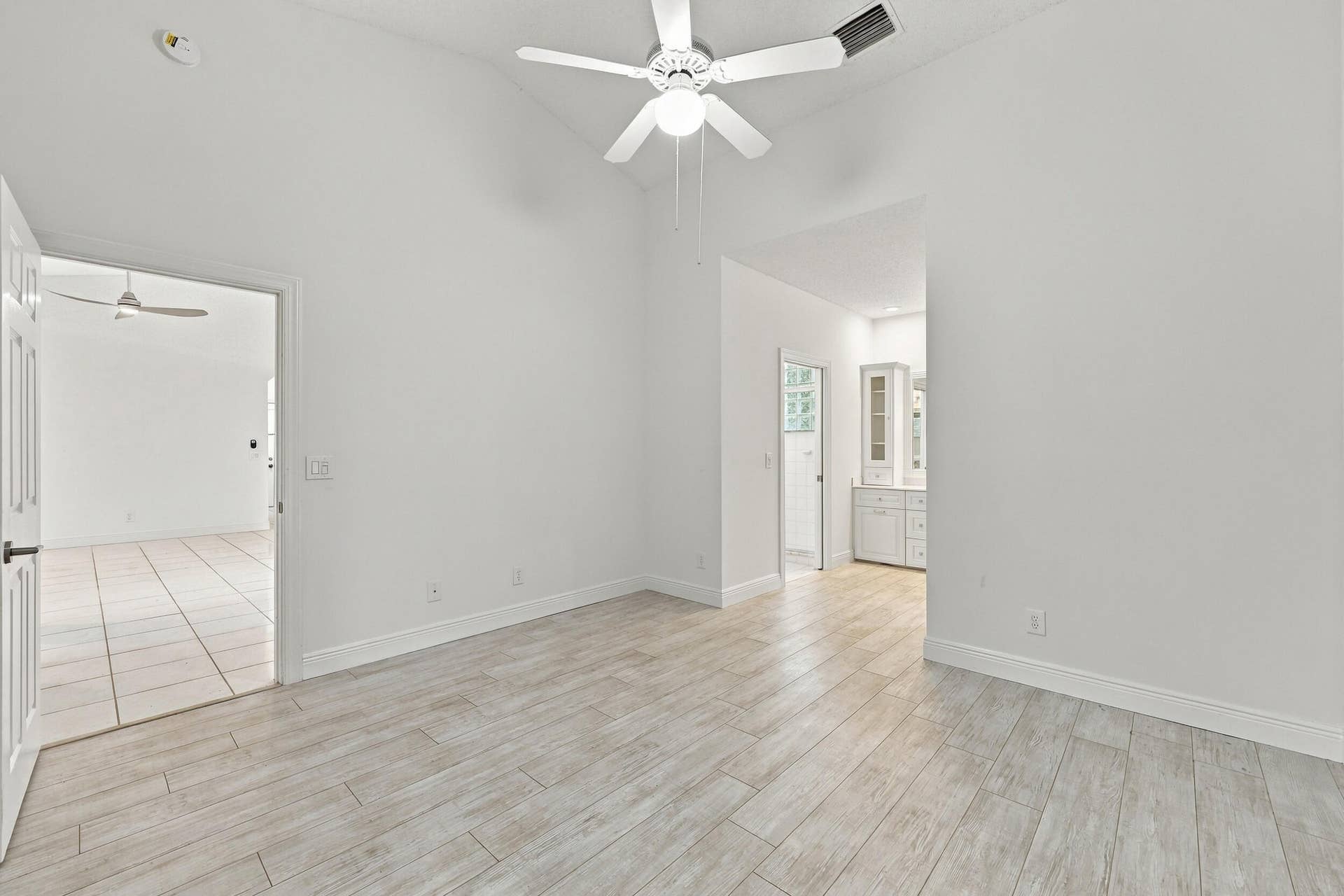 8292 WATERLINE Drive, #106, Boynton Beach, FL 33472 Vaulted ceiling with a ceiling fan, wood-finish tile flooring, white interior walls, and built-in cabinetry with glass-front uppers