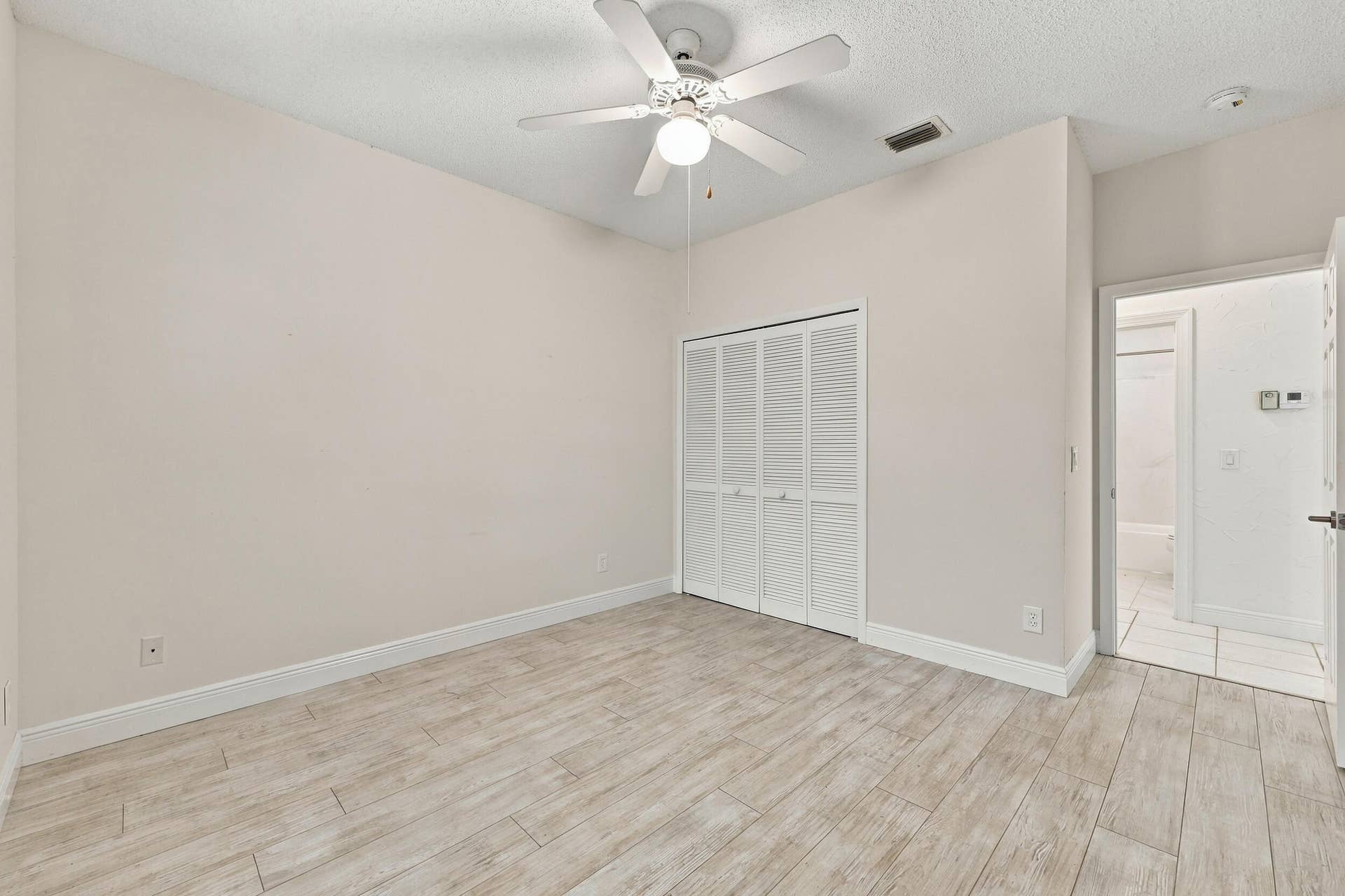 8292 WATERLINE Drive, #106, Boynton Beach, FL 33472 Wood-finish flooring, ceiling fan with integrated lighting, louvered bi-fold closet doors, and recessed ceiling vent