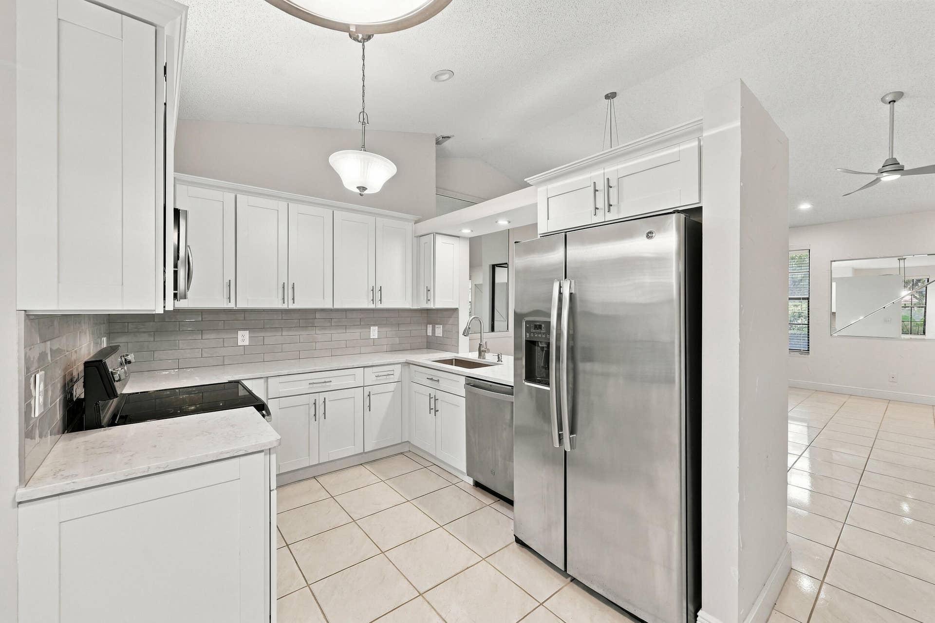 8292 WATERLINE Drive, #106, Boynton Beach, FL 33472 Kitchen with white shaker-style cabinetry, stainless steel appliances, light-toned countertops, tile flooring, and a subway tile backsplash