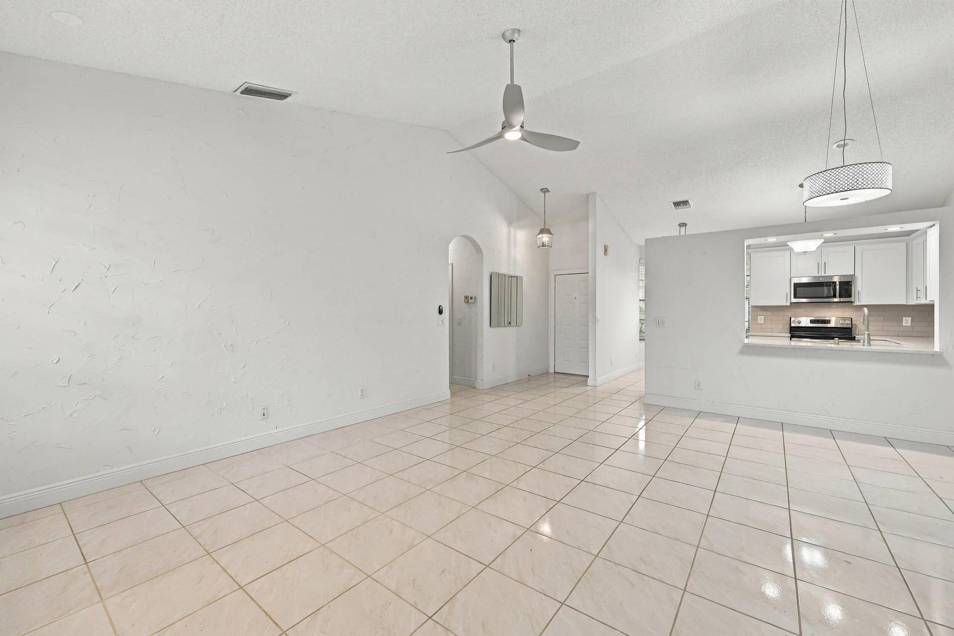 8292 Waterline Drive, #106, Boynton Beach, FL 33472 Vaulted ceilings, tiled flooring, arched doorway, and recessed kitchen pass-through