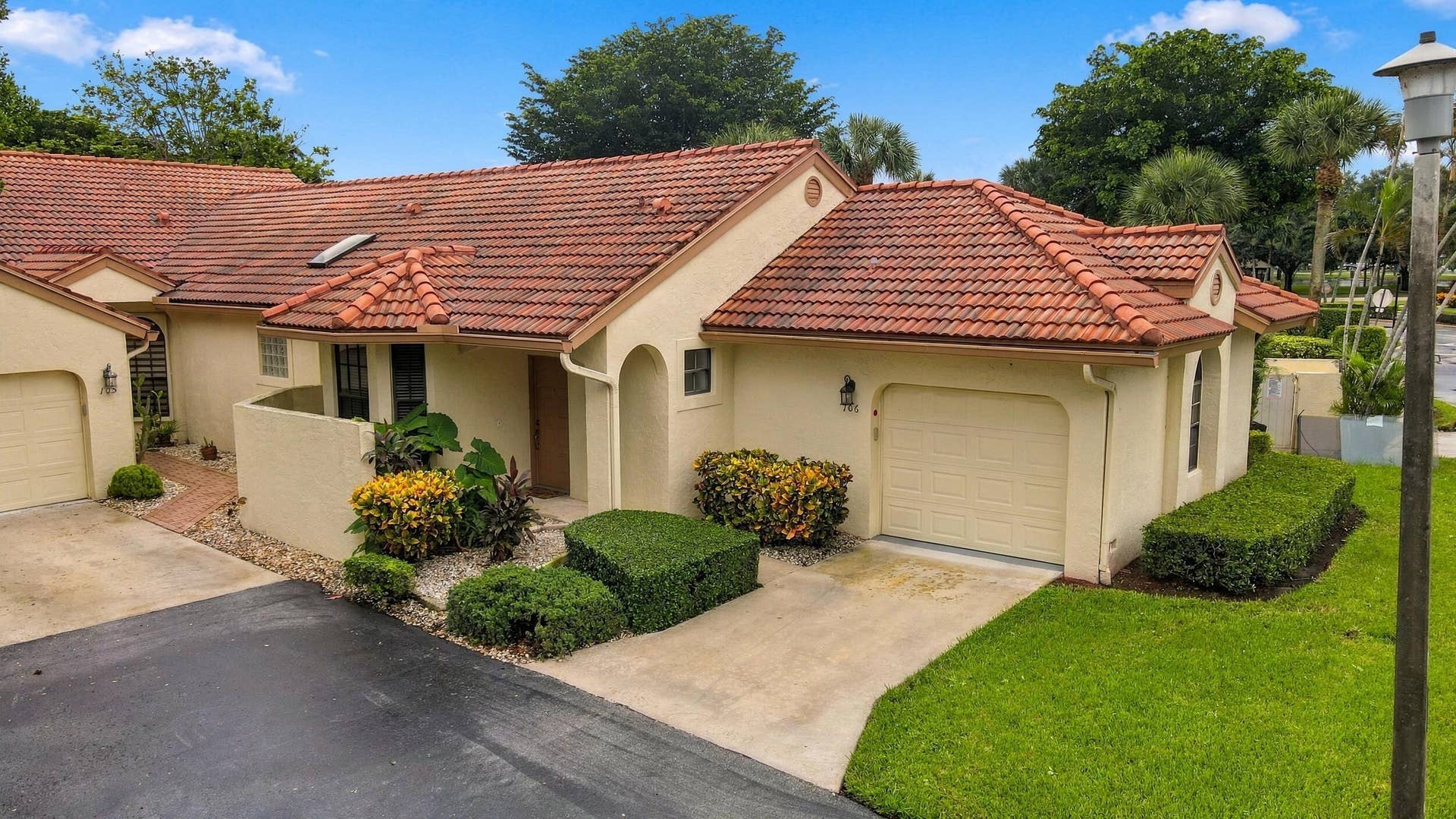8292 Waterline Drive, #106, Boynton Beach, FL 33472 Mediterranean-inspired exterior with a terracotta tile roof, stucco facade, attached garage, and manicured landscaping