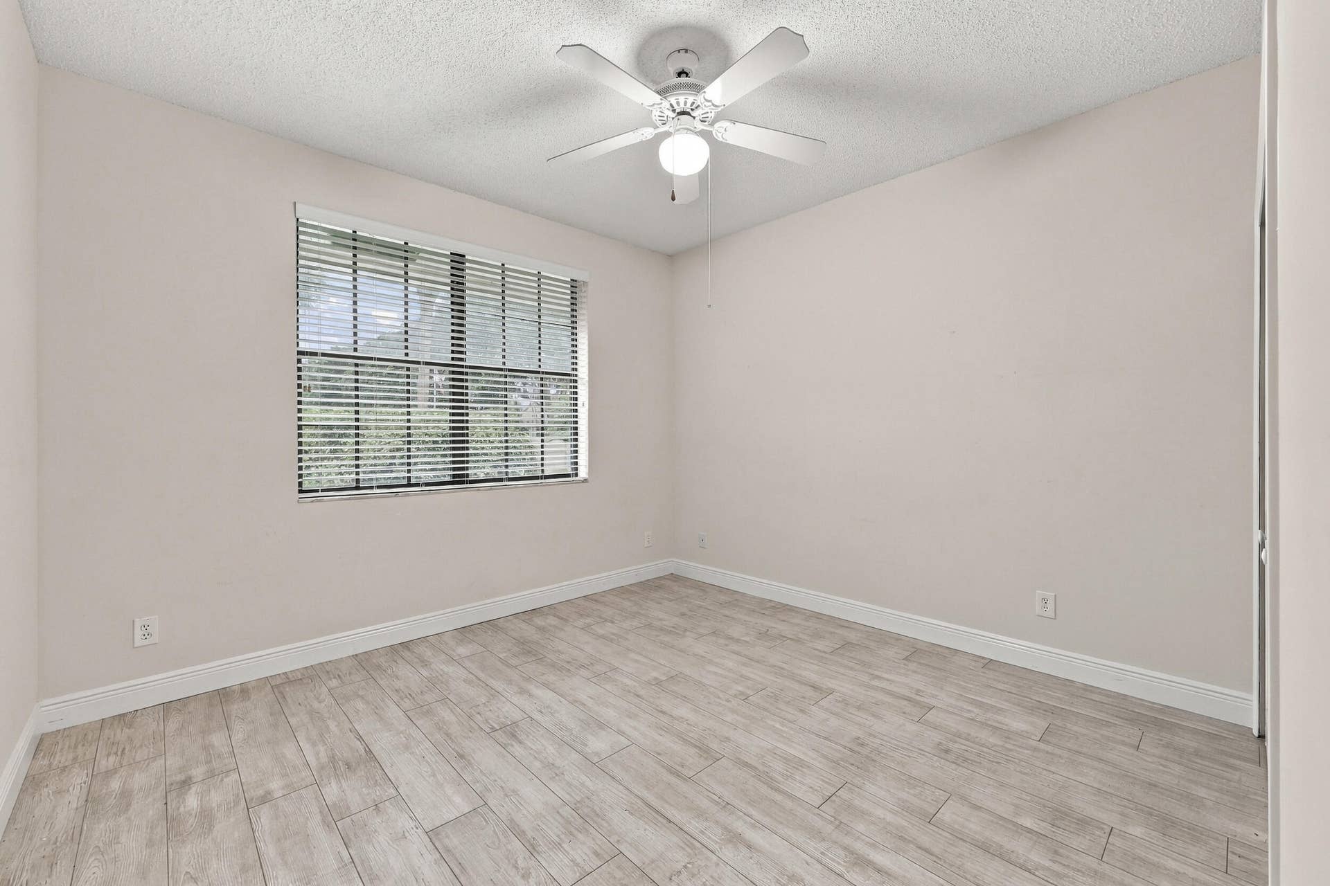 8292 Waterline Drive, #106, Boynton Beach, FL 33472 Wood-finish flooring with white baseboards, a window with blinds, and a ceiling fan with integrated lighting