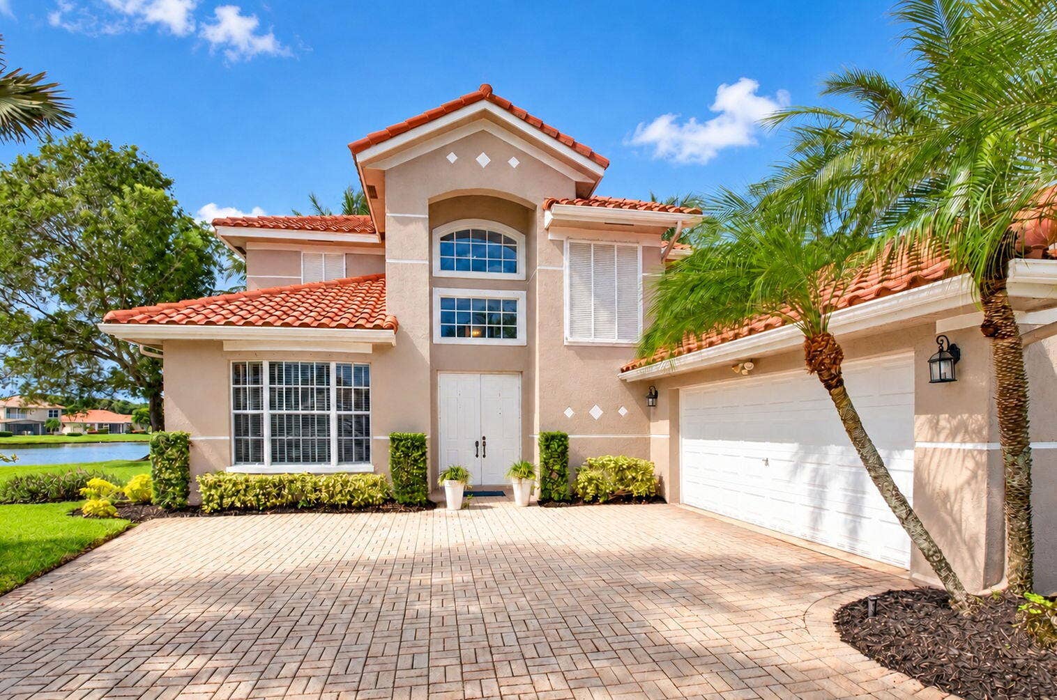 6610 Aston Lane, Boynton Beach, FL 33437 arched and rectangular windows, a double-door entry, and an integrated two-car garage