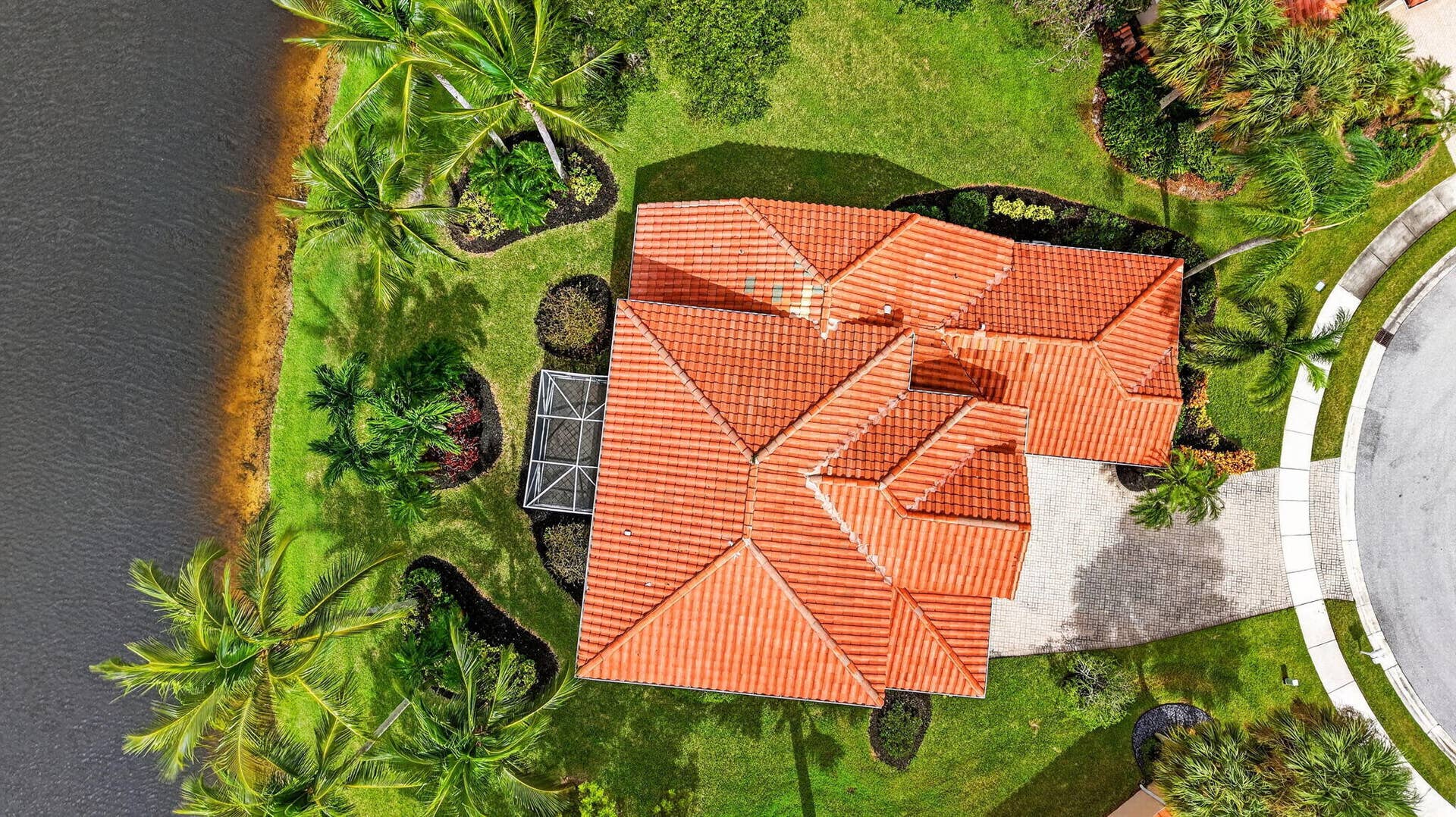 6610 Aston Lane, Boynton Beach, FL 33437 Tile roof residence with extensive green landscaping, a paved driveway, and waterfront access