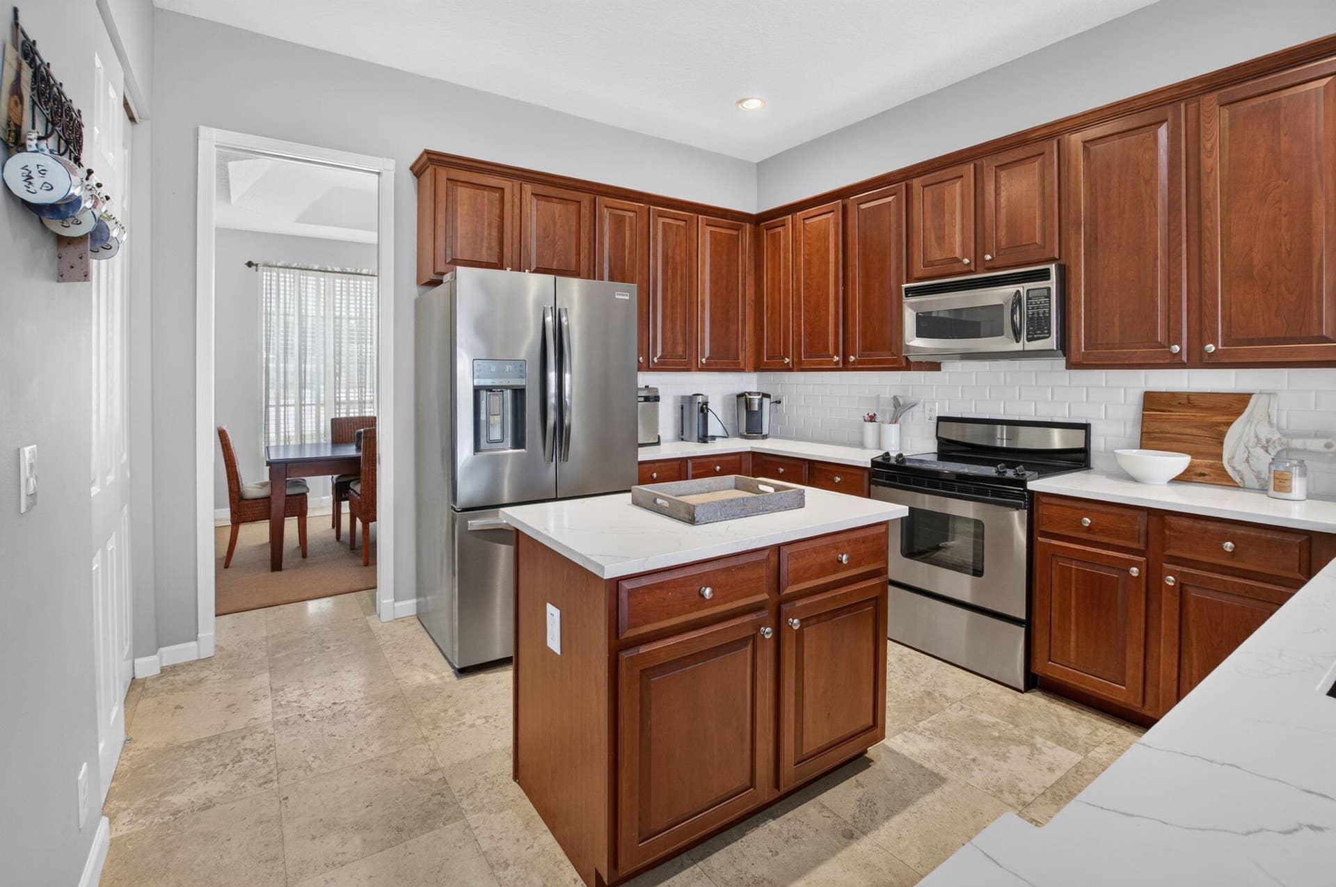 6610 Aston Lane, Boynton Beach, FL 33437 Kitchen featuring a center island, wood-finish cabinetry, stainless steel appliances, white subway tile backsplash, and light-toned flooring