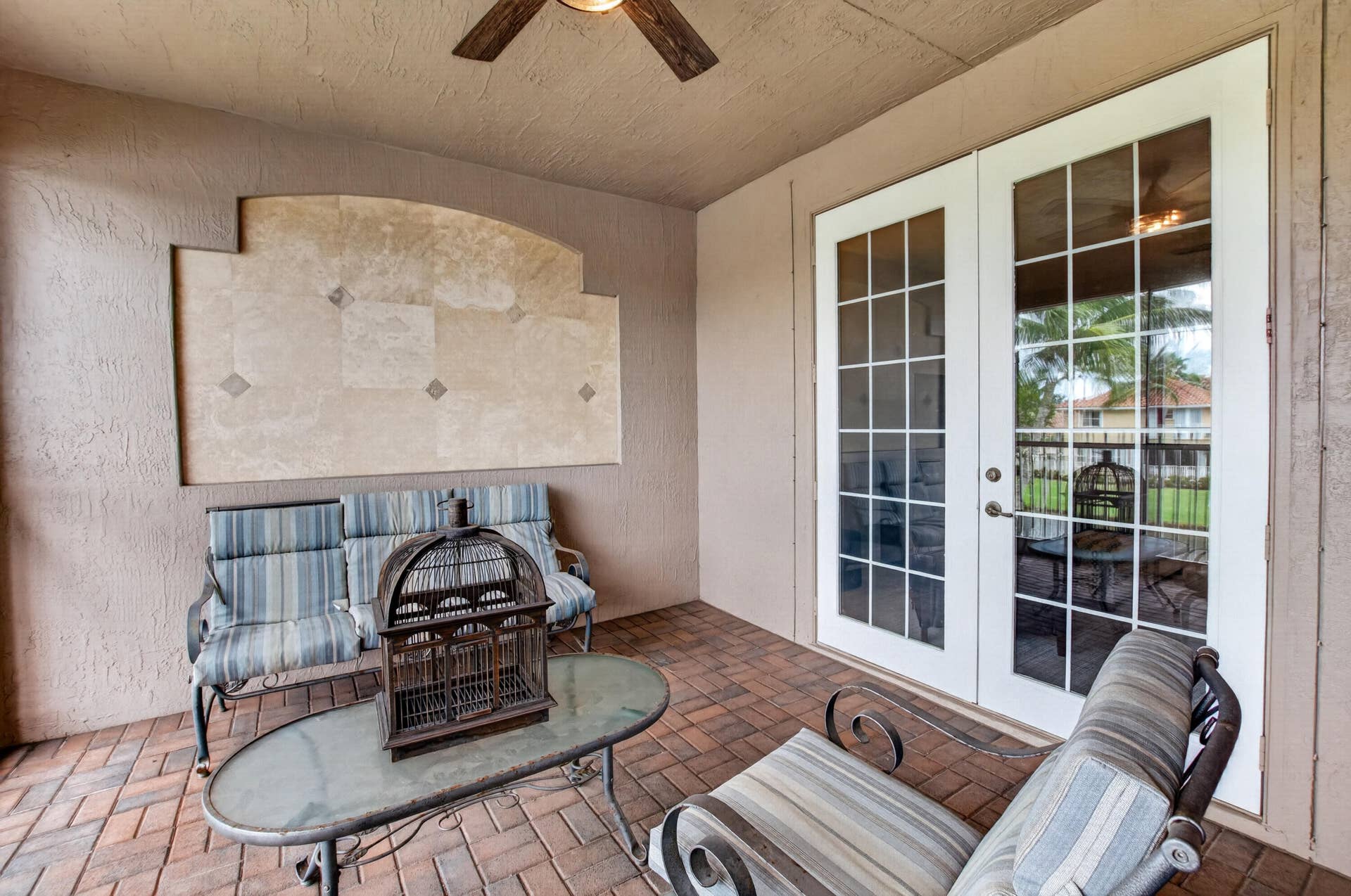 6610 Aston Lane, Boynton Beach, FL 33437 Covered patio featuring brick paver flooring, overhead ceiling fan, and double French doors with grid-patterned glass panels