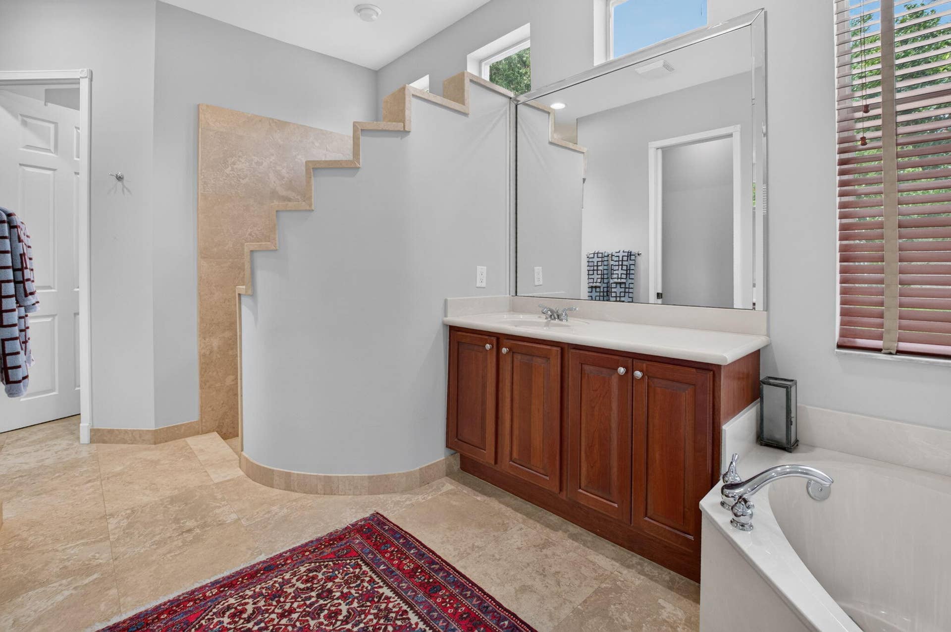 6610 Aston Lane, Boynton Beach, FL 33437 Recessed bathtub with deck-mounted faucet, wood-finish vanity with countertop, large wall-mounted mirror, and tile flooring