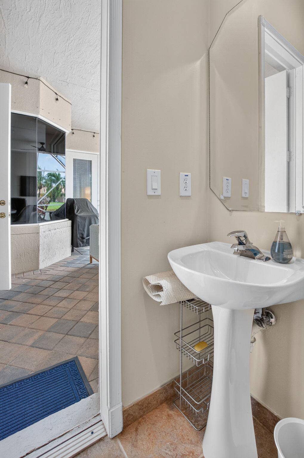 6610 Aston Lane, Boynton Beach, FL 33437 Pedestal sink with chrome faucet, octagonal wall mirror, and neutral wall paint