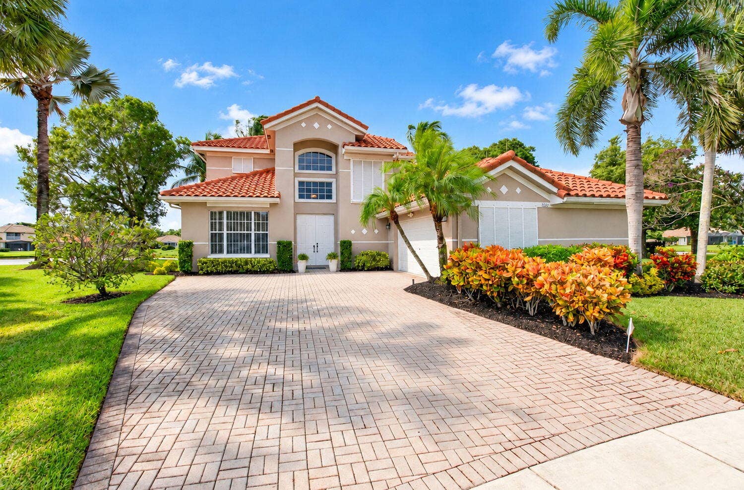6610 Aston Lane, Boynton Beach, FL 33437 Tile roof residence featuring a paver driveway, established palm trees, and manicured landscaping