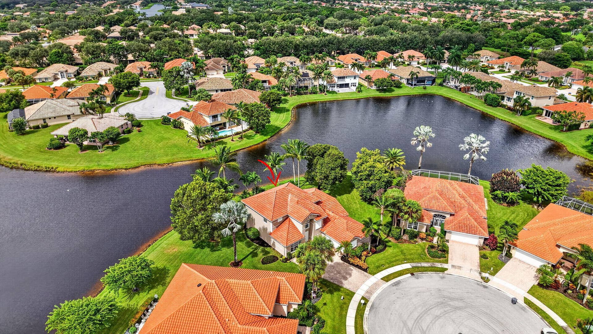 6610 Aston Lane, Boynton Beach, FL 33437 Waterfront property with a terracotta tile roof, lush landscaping, and a paver driveway