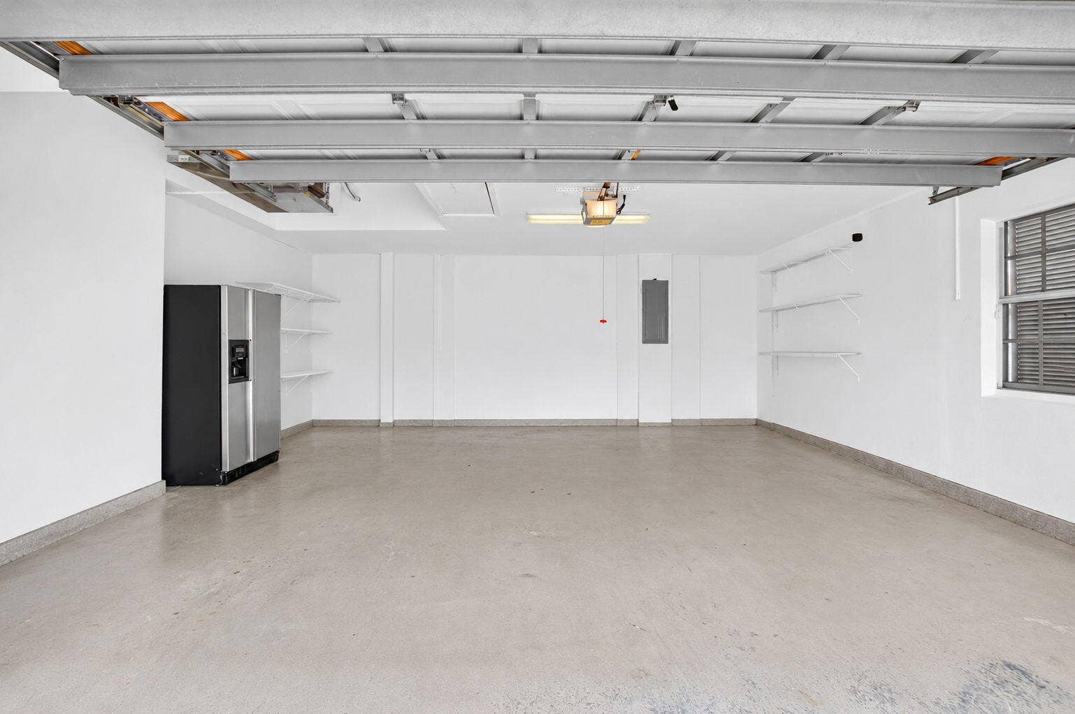 6610 Aston Lane, Boynton Beach, FL 33437 Spacious garage with exposed ceiling beams, built-in shelving, concrete flooring, and an integrated window
