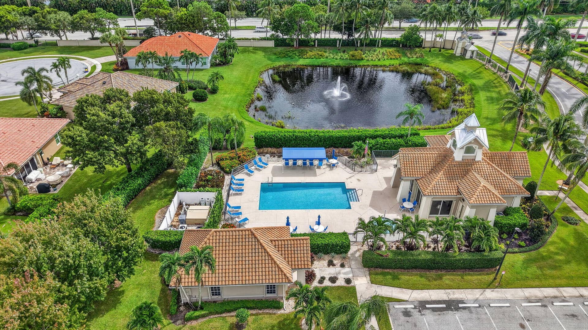 6610 Aston Lane, Boynton Beach, FL 33437 Community pool with surrounding patio, a separate structure with a tiled roof, and a fountain-equipped pond