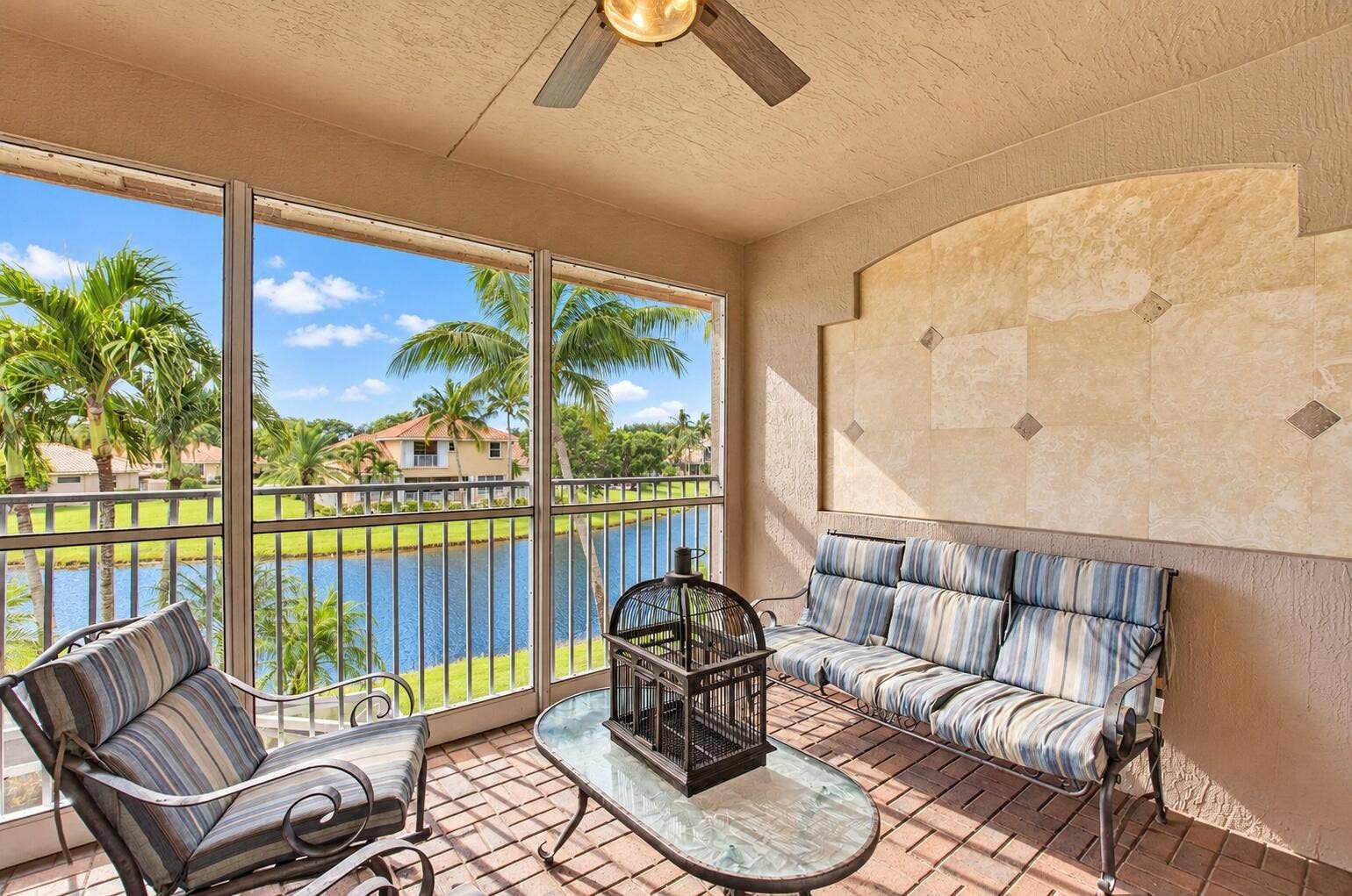 6610 Aston Lane, Boynton Beach, FL 33437 Screened balcony featuring a ceiling fan, brick-patterned flooring, and a decorative wall with stone accents