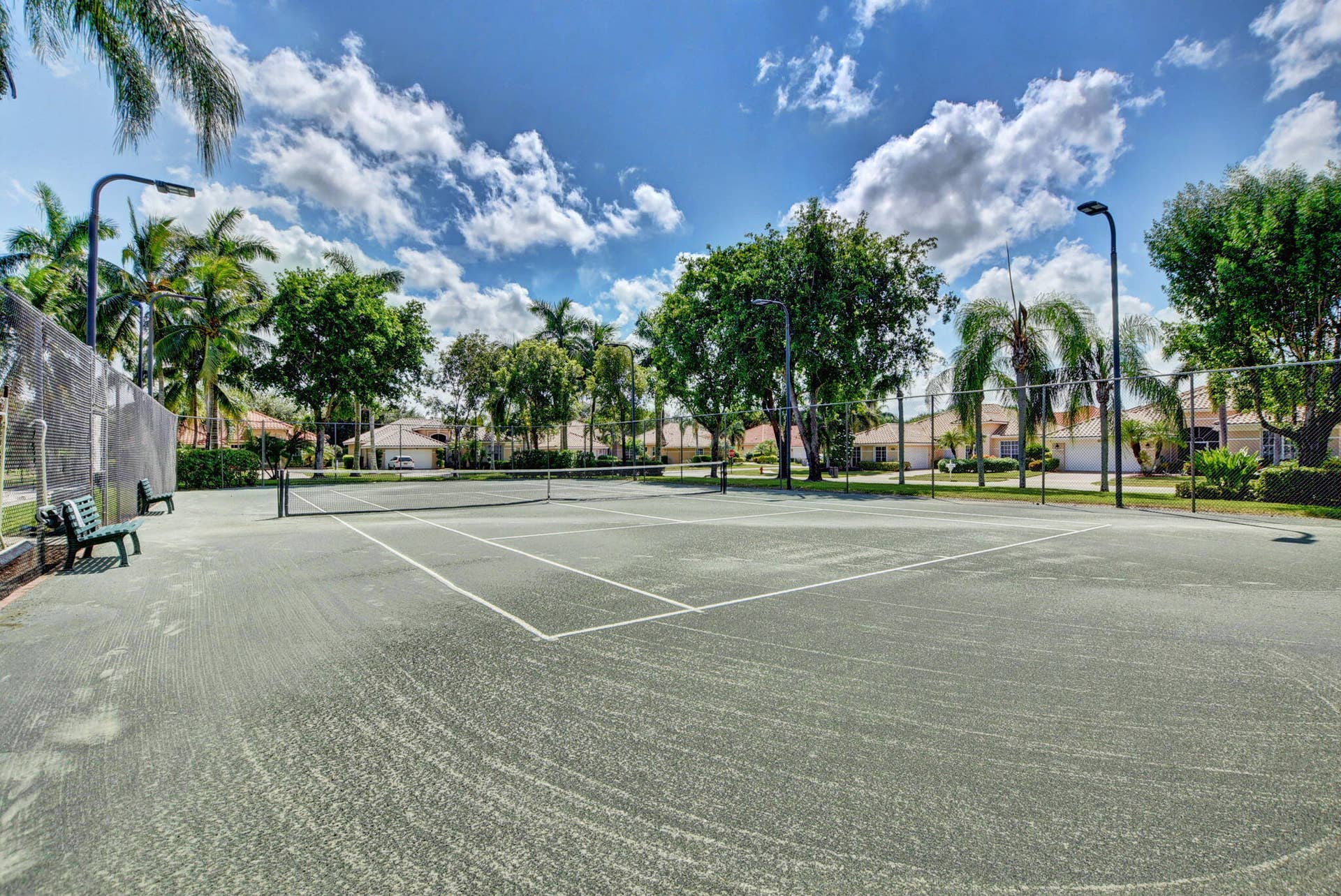 6610 Aston Lane, Boynton Beach, FL 33437 Full-size tennis court featuring court lighting, fencing, and a bench