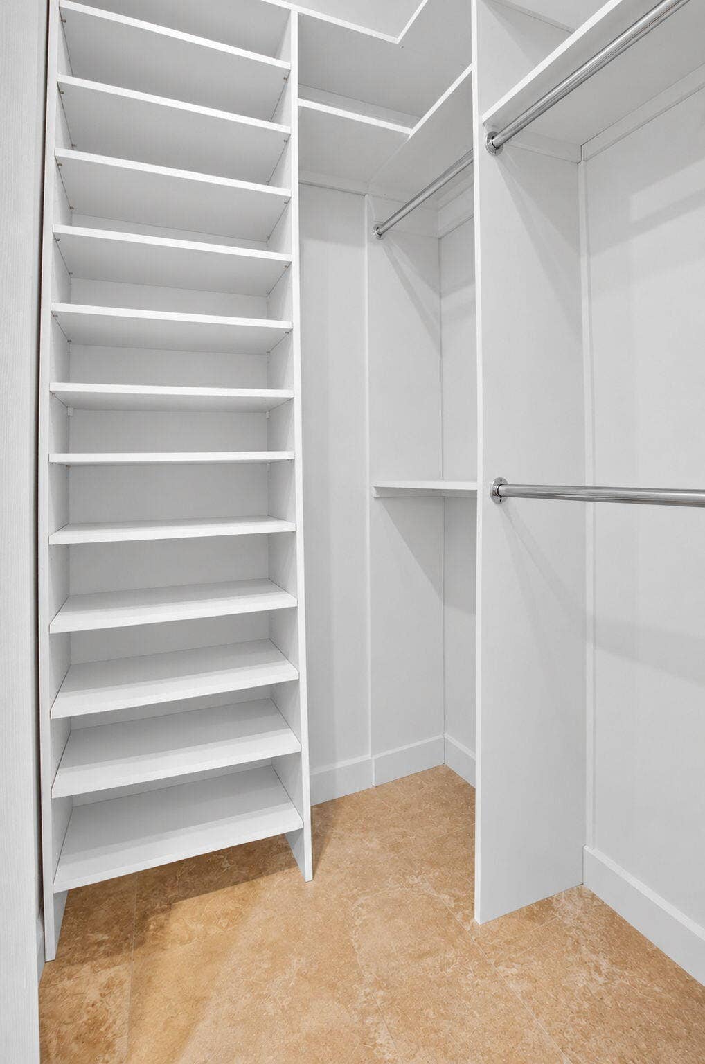 6610 Aston Lane, Boynton Beach, FL 33437 Built-in closet system featuring white shelving, multiple hanging rods, and a natural stone tile floor