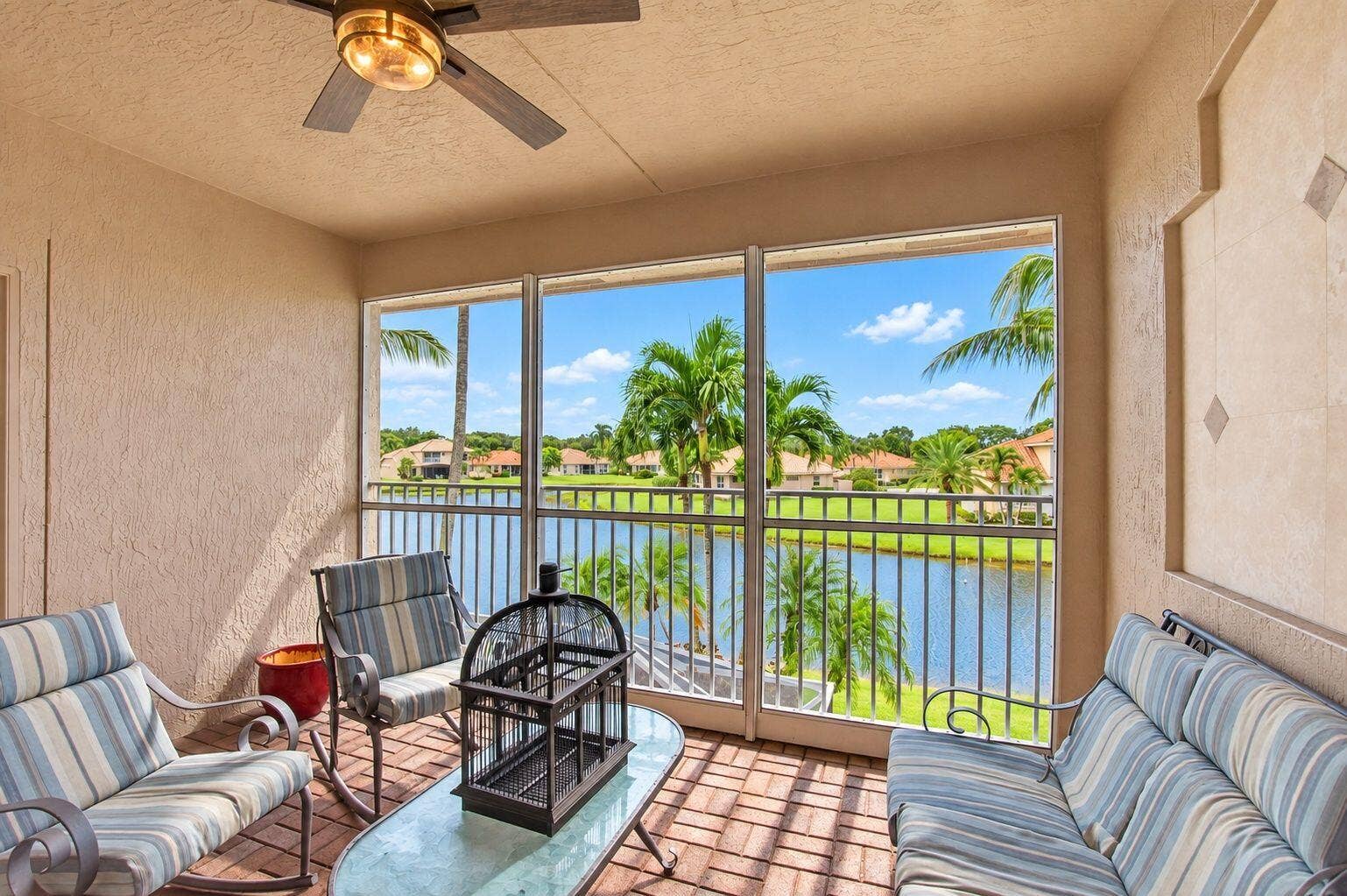 6610 Aston Lane, Boynton Beach, FL 33437 Screened balcony with textured walls, a ceiling fan, and a metal railing overlooking a body of water