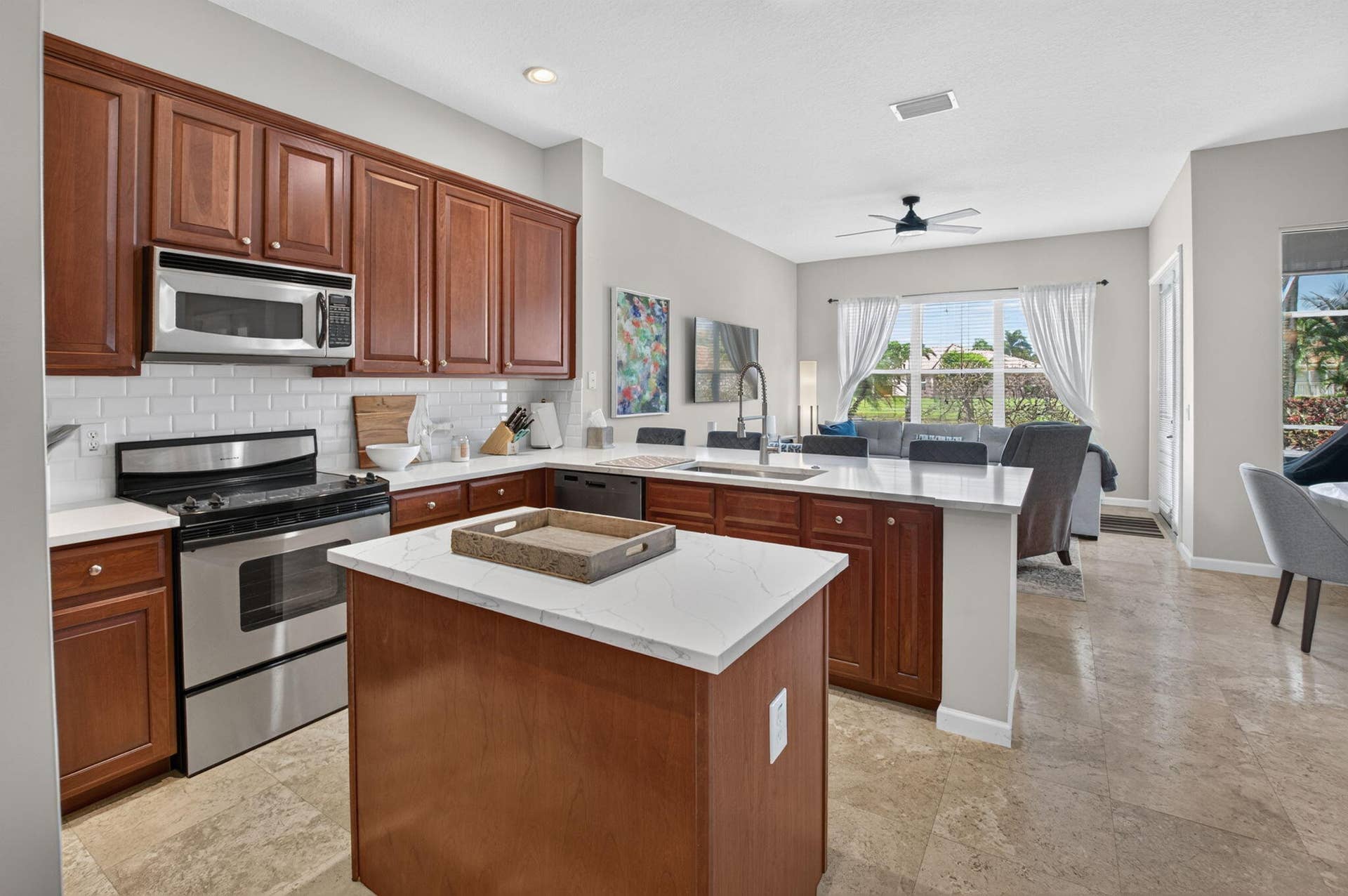 6610 Aston Lane, Boynton Beach, FL 33437 Kitchen featuring wood-finish cabinetry, stainless steel appliances, white subway tile backsplash, and light-toned Quartz countertops