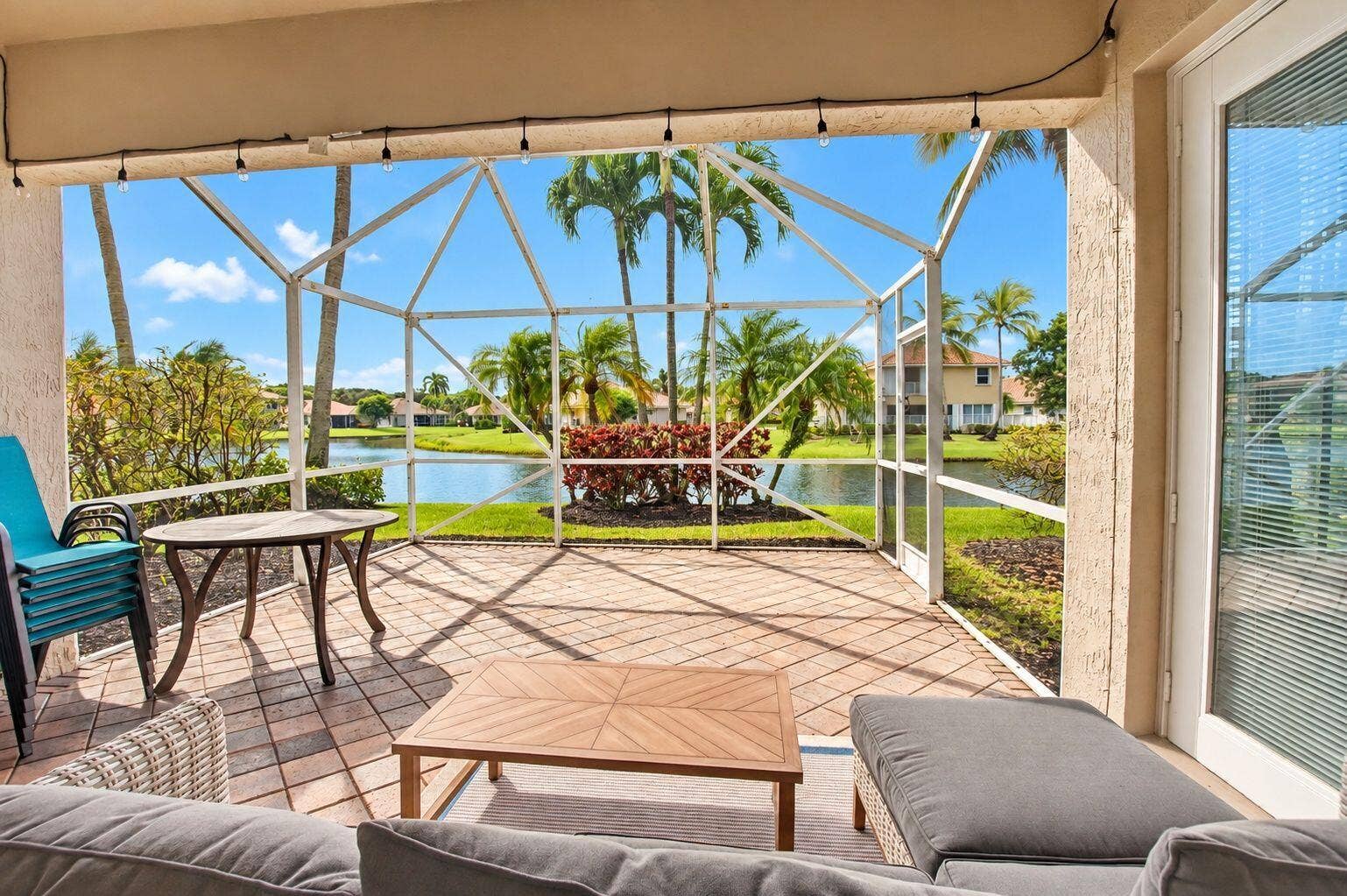 6610 Aston Lane, Boynton Beach, FL 33437 Screened patio with brick paver flooring, featuring a water element and mature palm trees