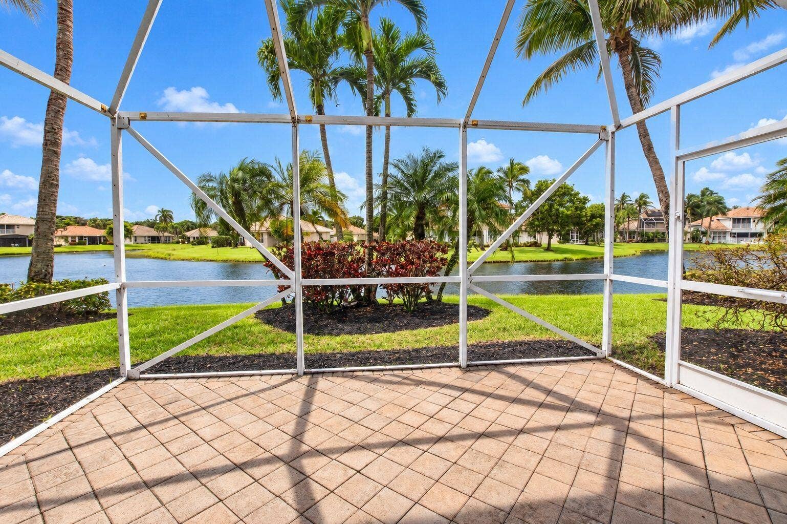 6610 Aston Lane, Boynton Beach, FL 33437 Sunsets!!!! on the Screened patio with paver flooring, overlooking a body of water with lush landscaping and mature palm trees