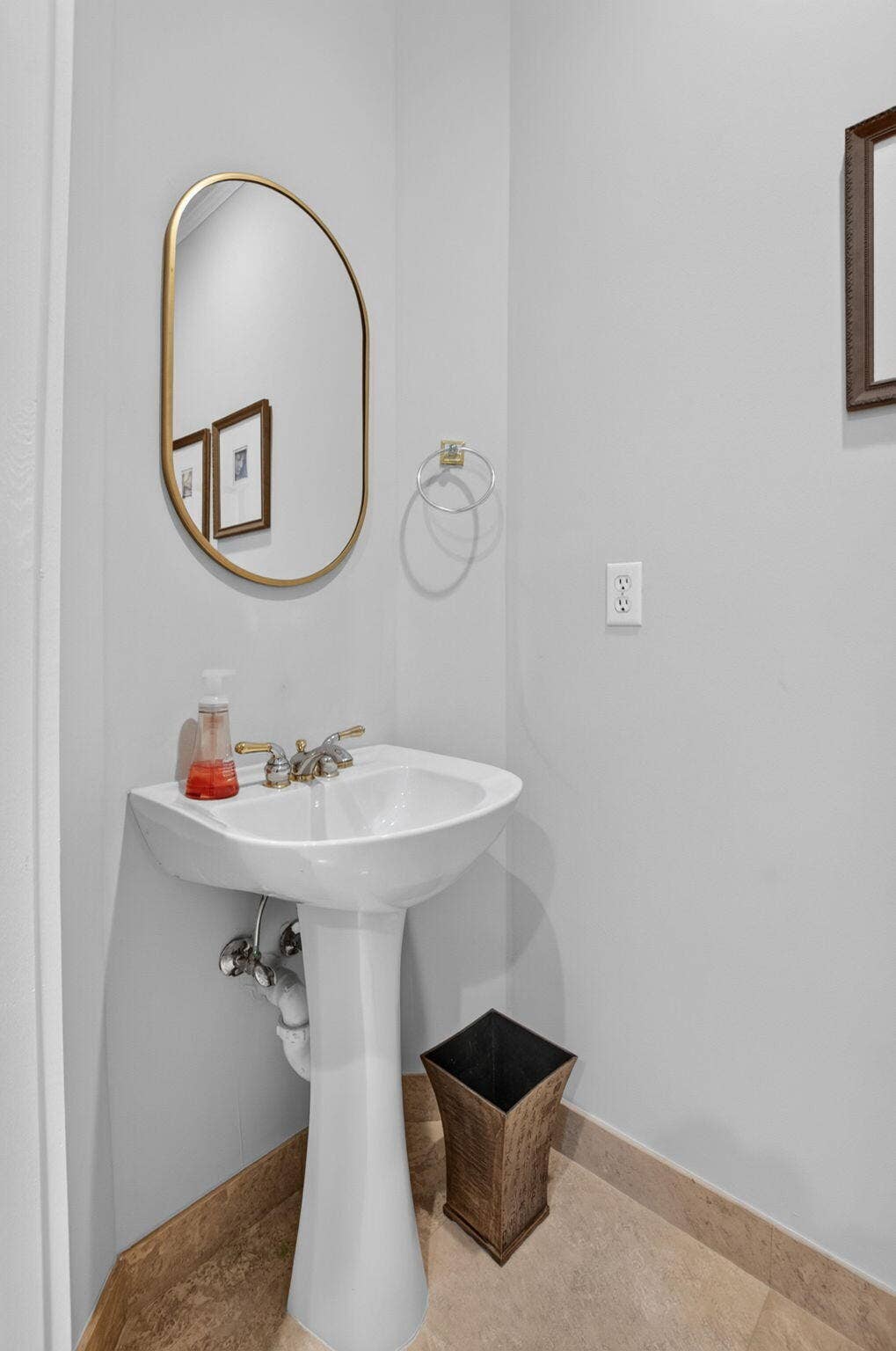 6610 Aston Lane, Boynton Beach, FL 33437 Pedestal sink with a polished brass-finish faucet, framed mirror, and tile flooring